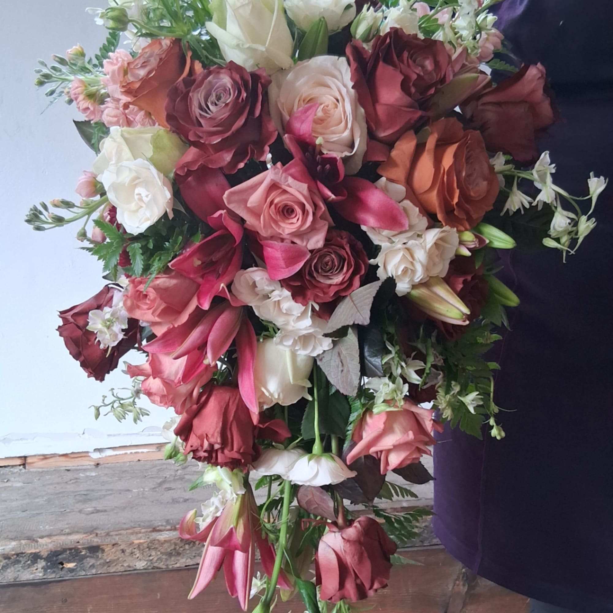 Large bouquet of roses and lilies in pink, white, and burgundy tones