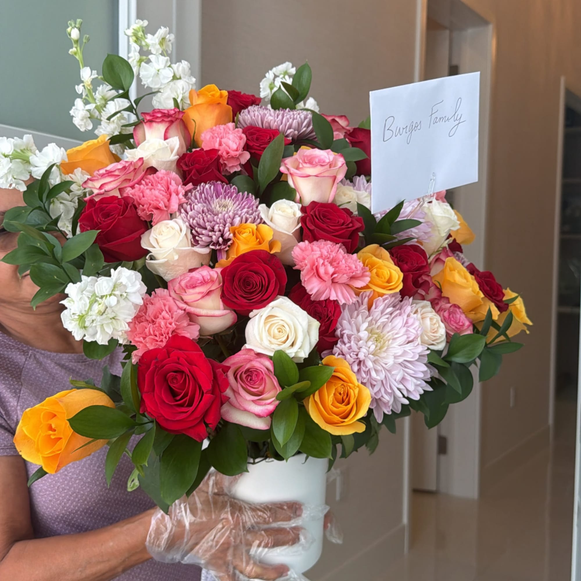 Large mixed bouquet of roses, carnations, and chrysanthemums in a white vase