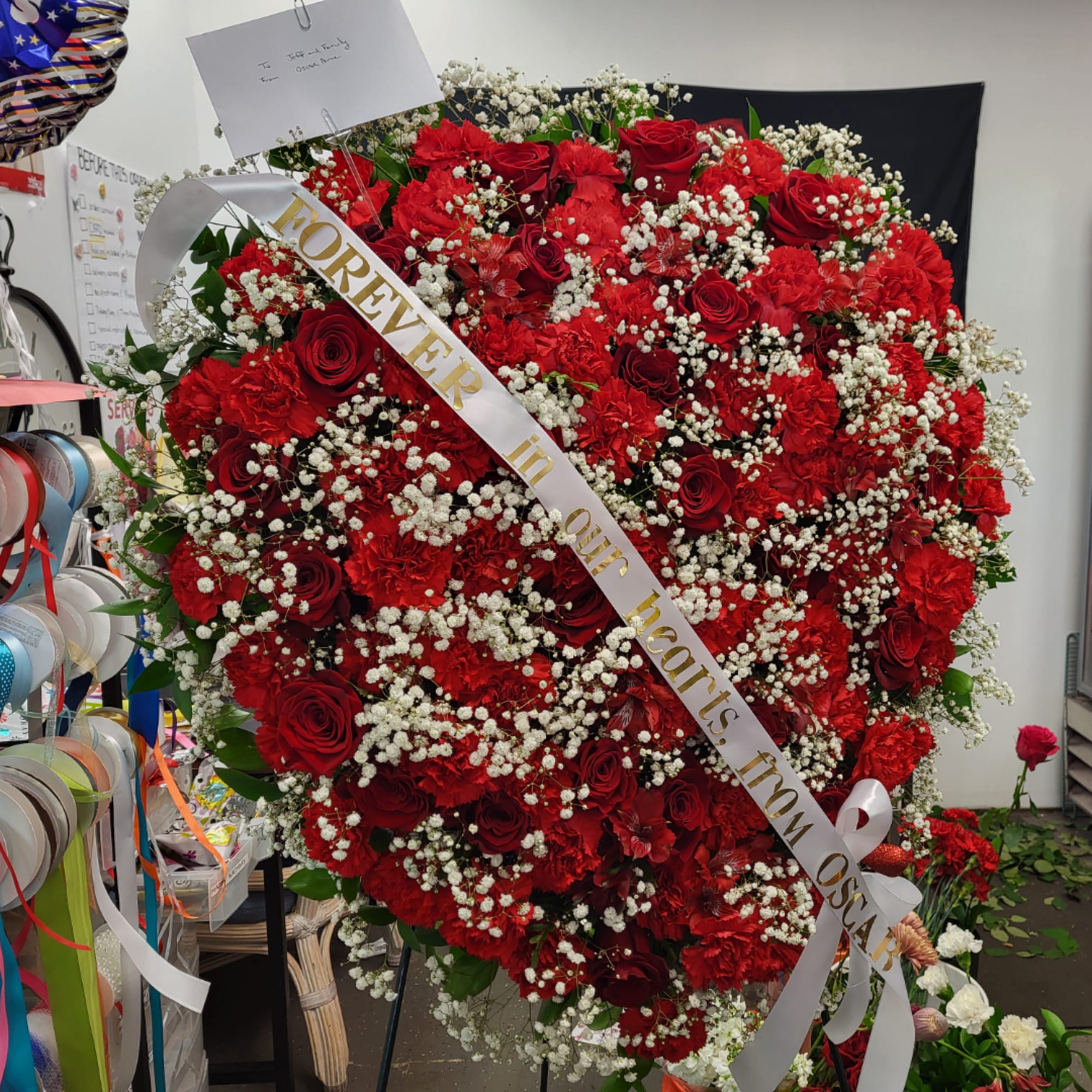 Large heart-shaped red rose and carnation arrangement with white baby's breath