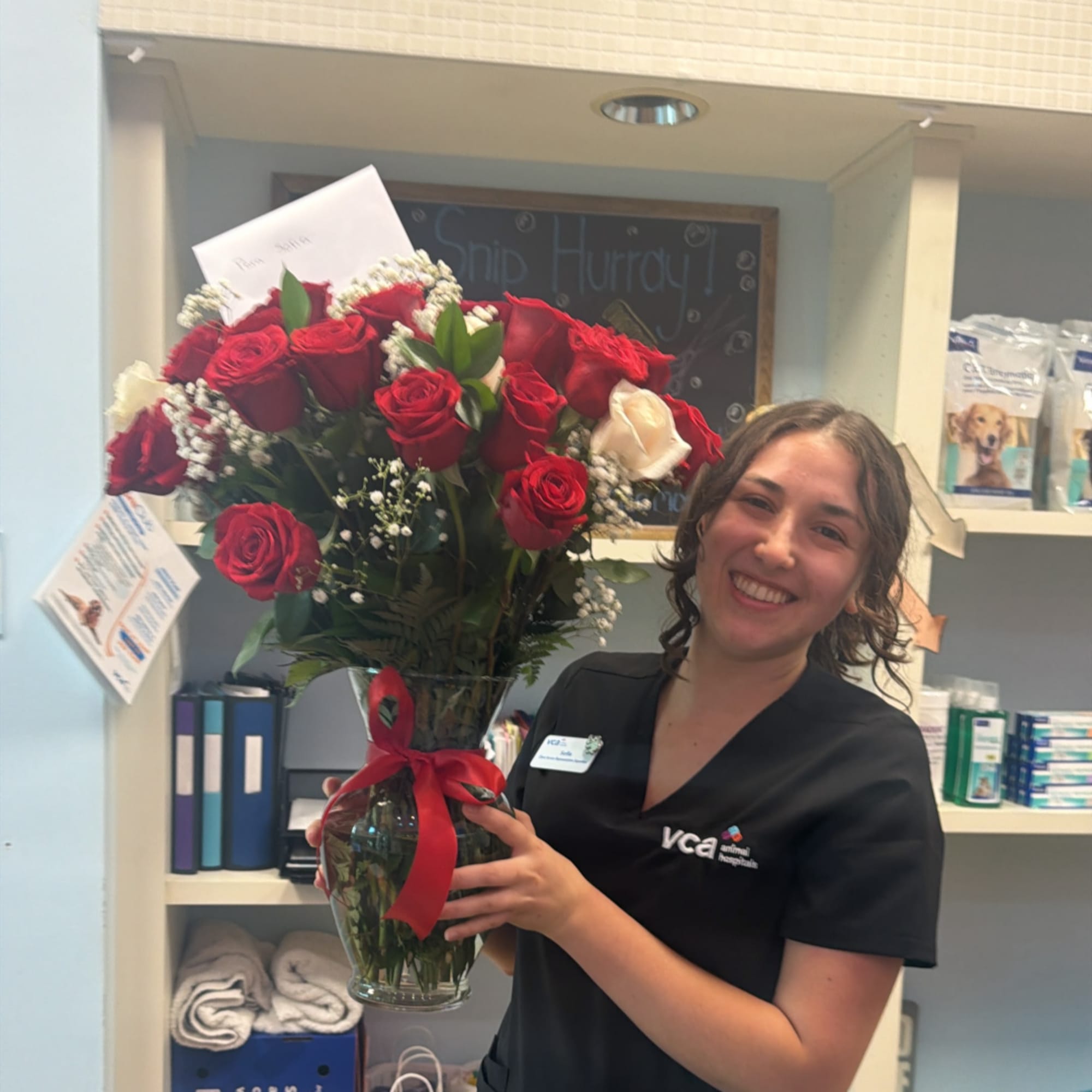 Woman holding a vase of red and white roses with a red ribbon