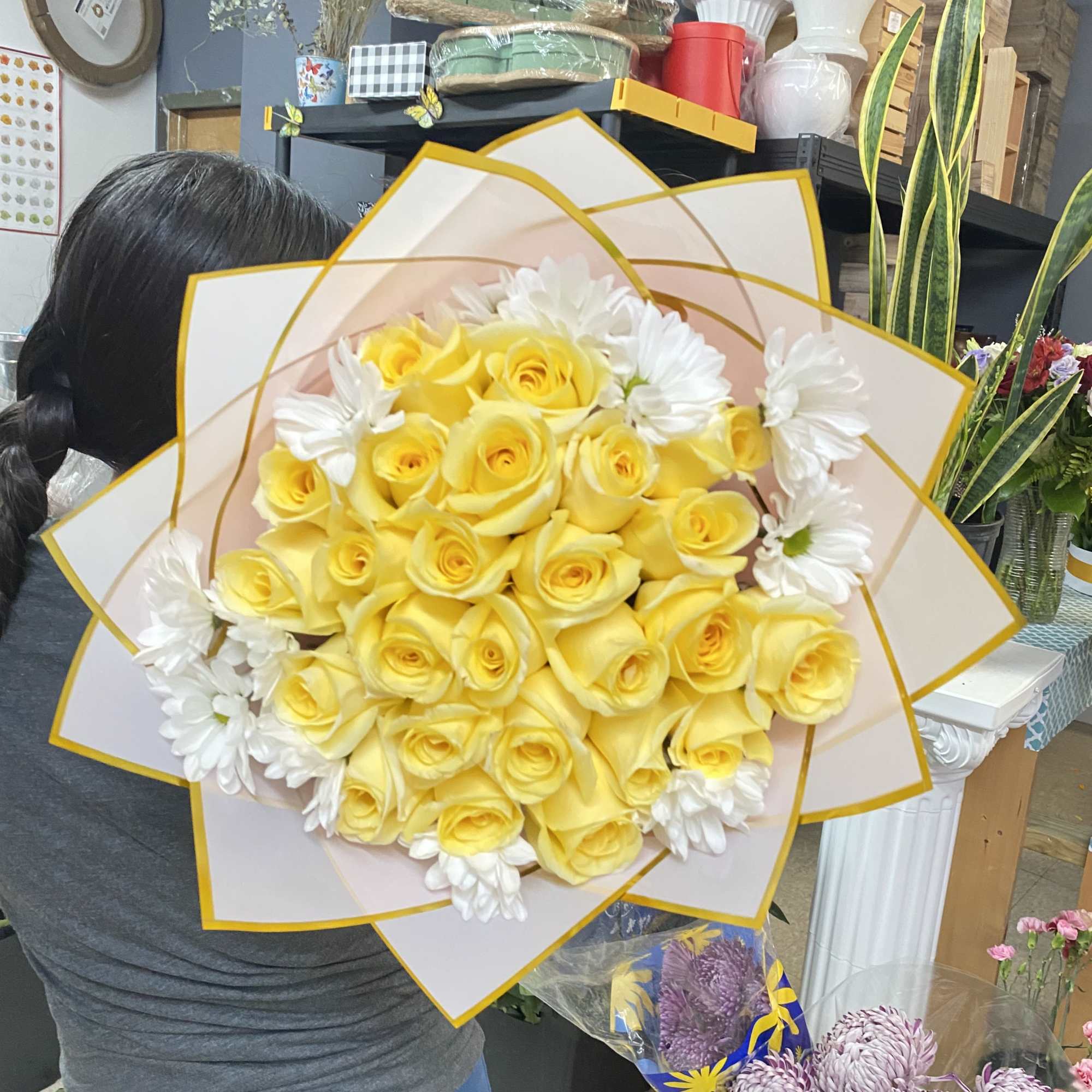 Yellow roses and white daisies arranged in layered paper wrap