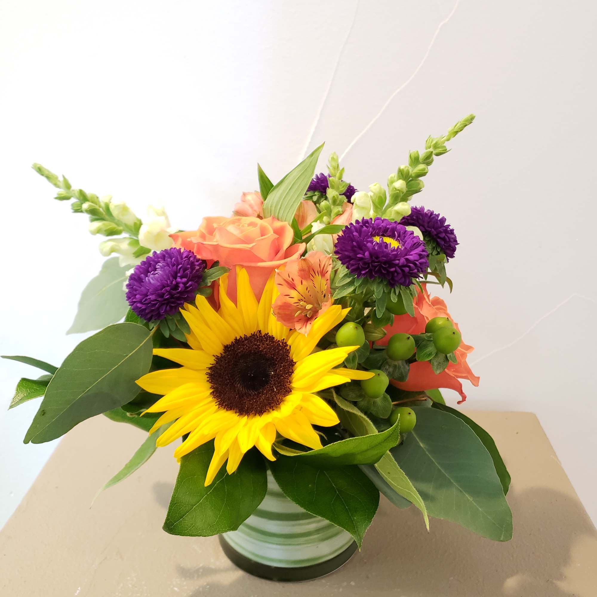 4" cylinder vase with alstromeria, aster, sunflowers, roses and snap dragons. 
