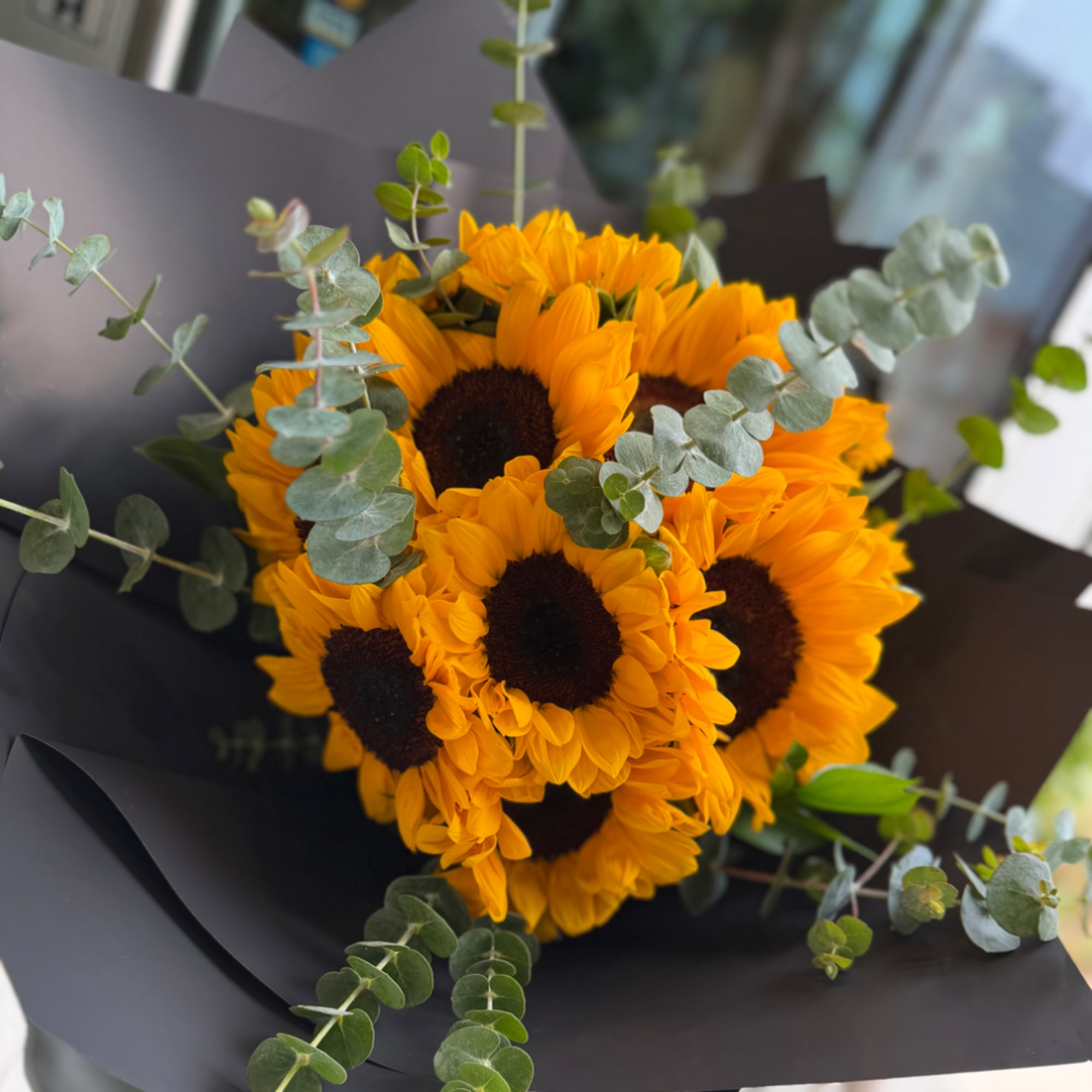 Bouquet of sunflowers wrapped in black paper with eucalyptus