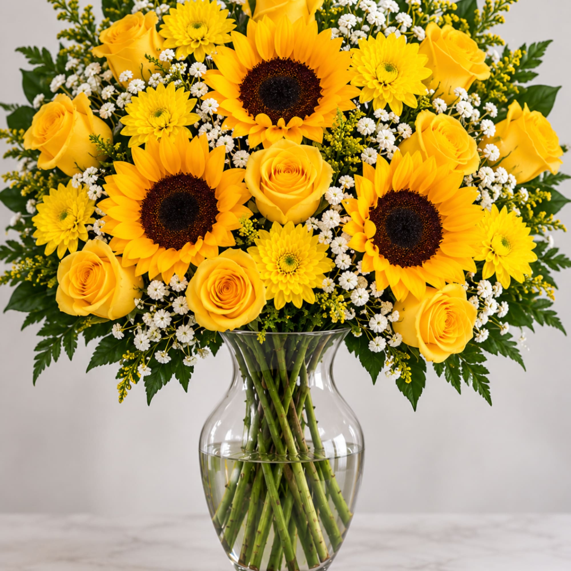 Yellow roses and sunflowers in a clear glass vase