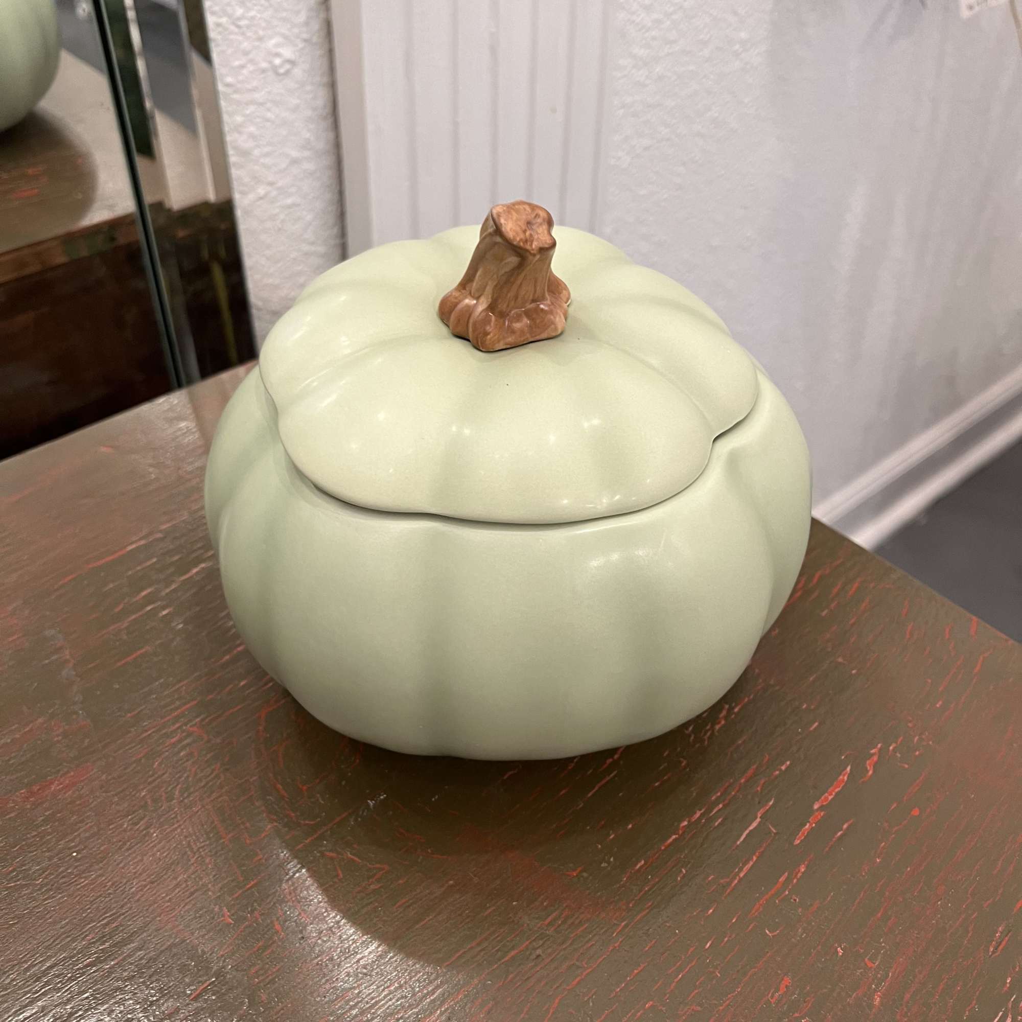 Ceramic pumpkin-shaped container with a lid on a table