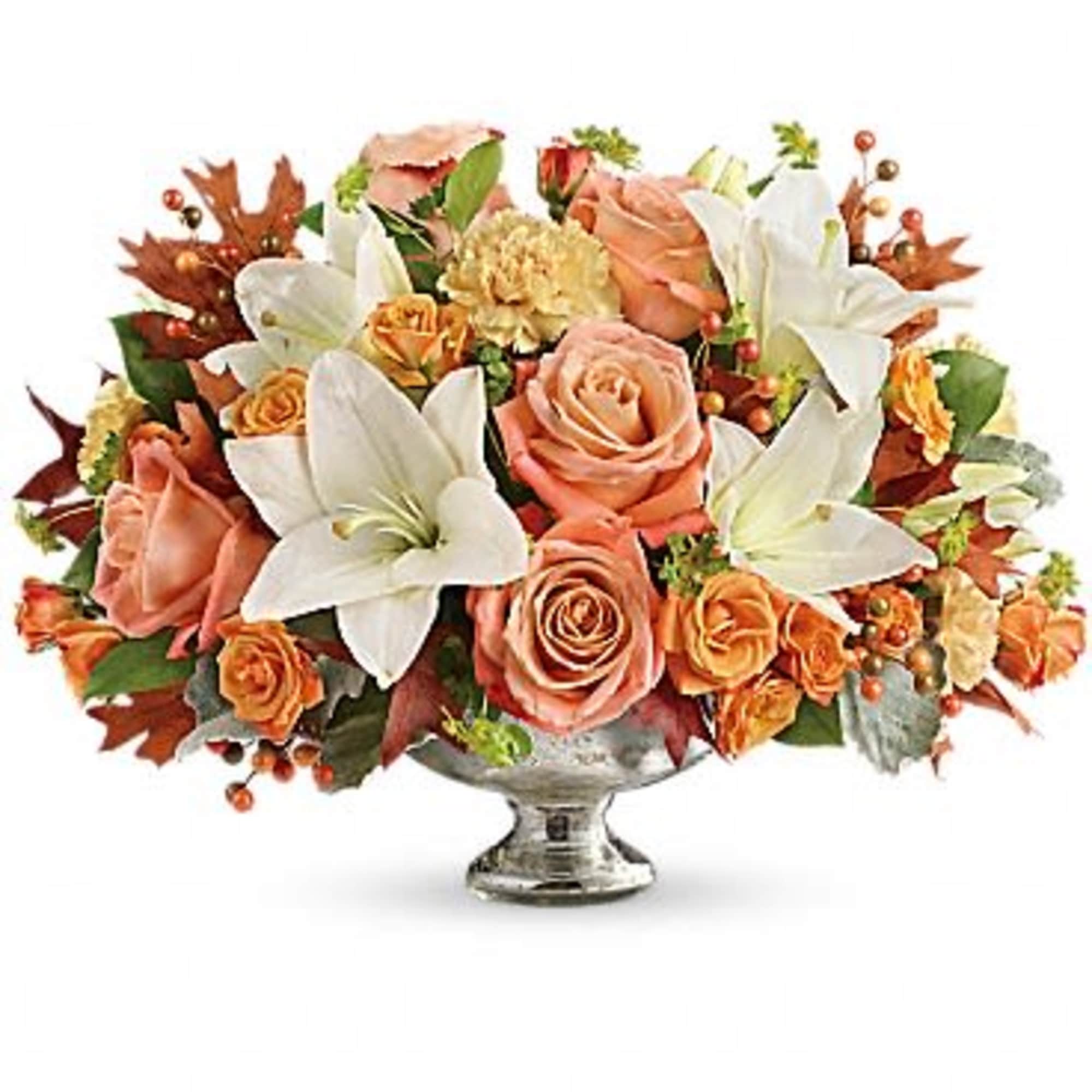 Peach roses and white lilies arranged in a silver pedestal vase