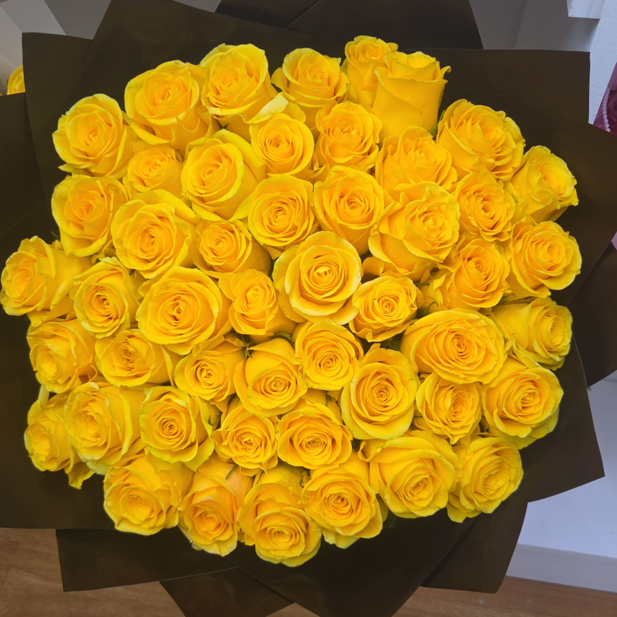 Bouquet of yellow roses wrapped in dark paper