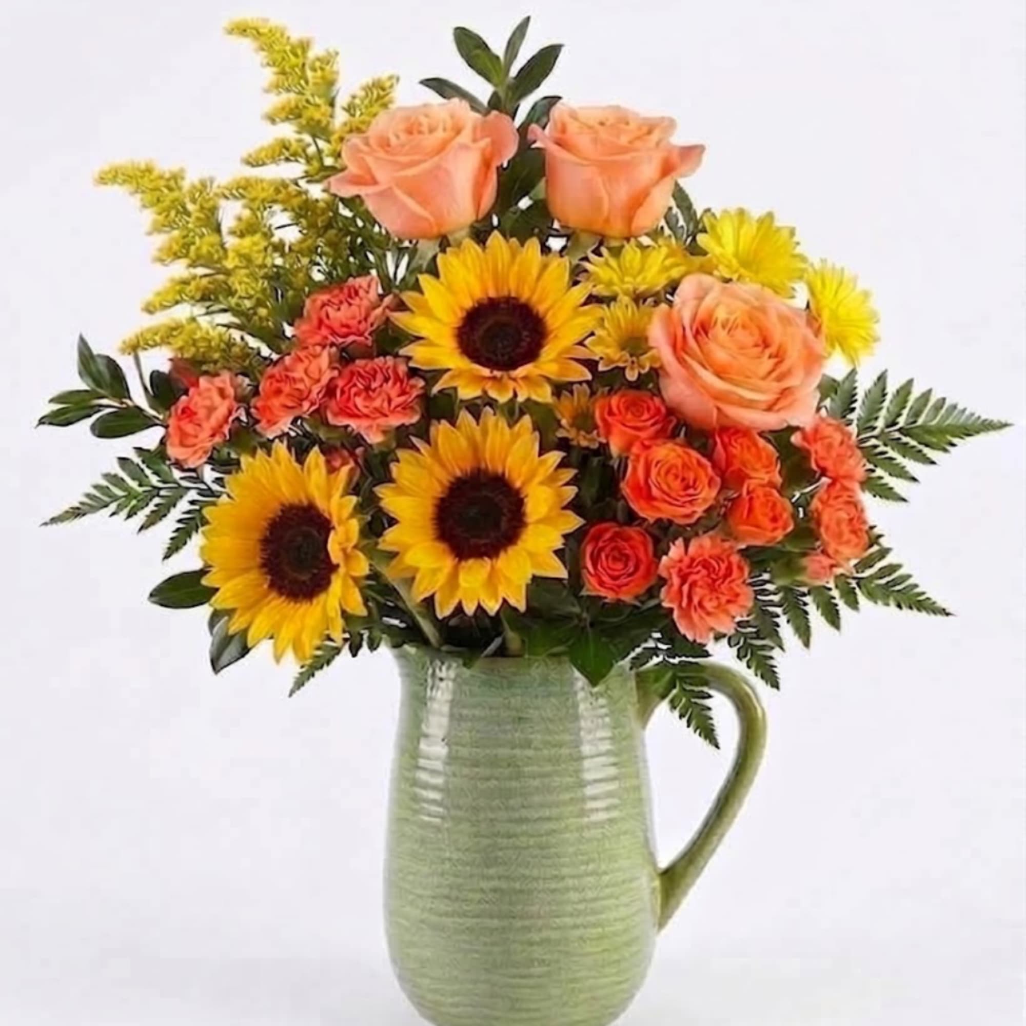 Bouquet of sunflowers, peach roses, and orange carnations in a green pitcher