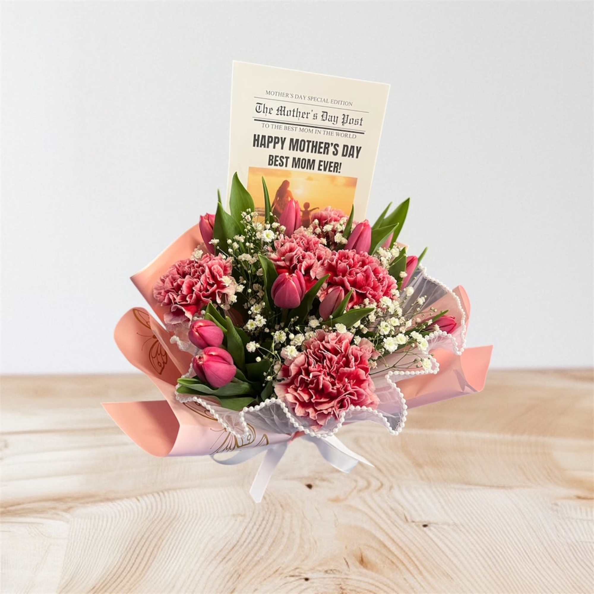 Pink carnation and tulip bouquet wrapped in pink paper with a Happy Mother's Day card