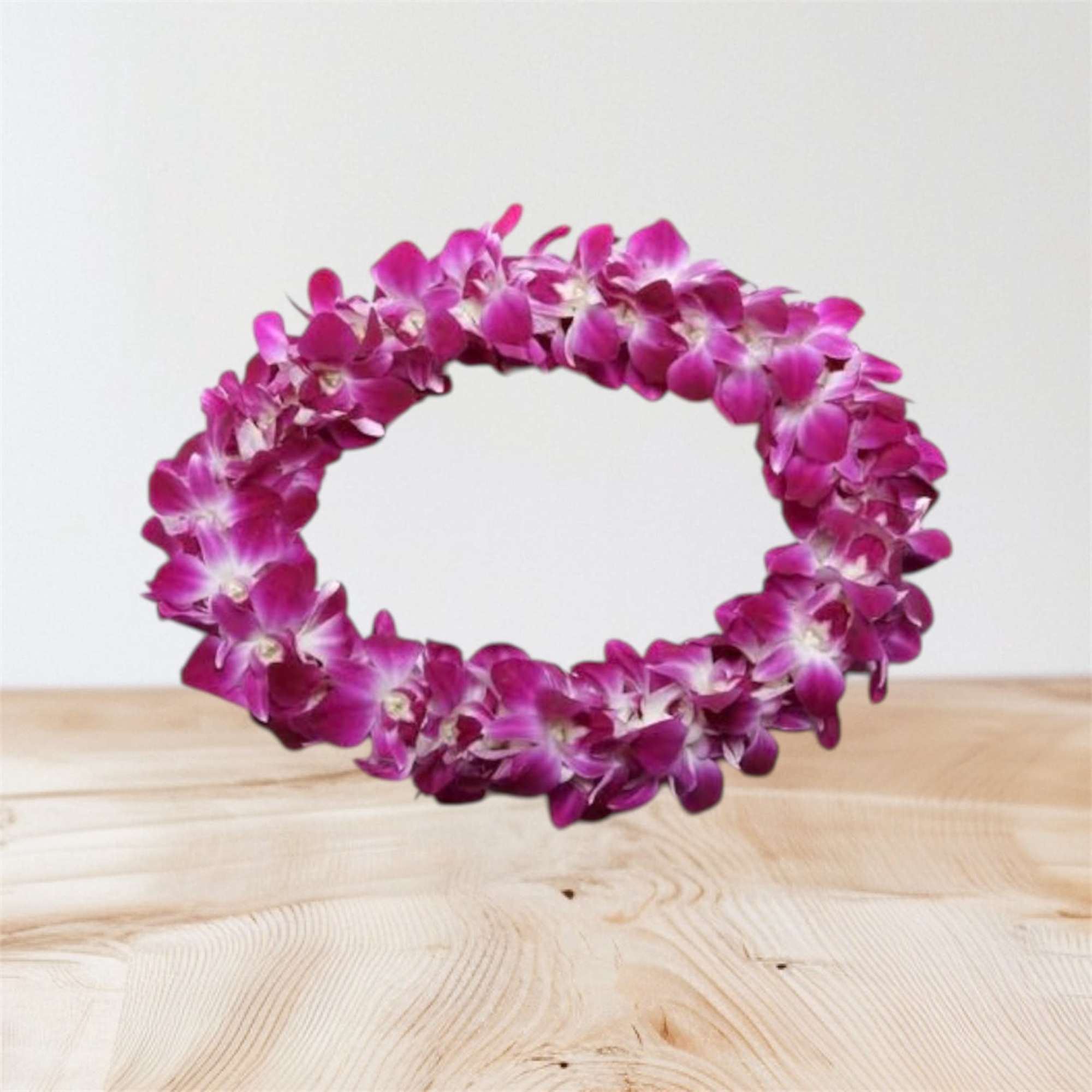 Purple orchid flower lei on a light wooden surface