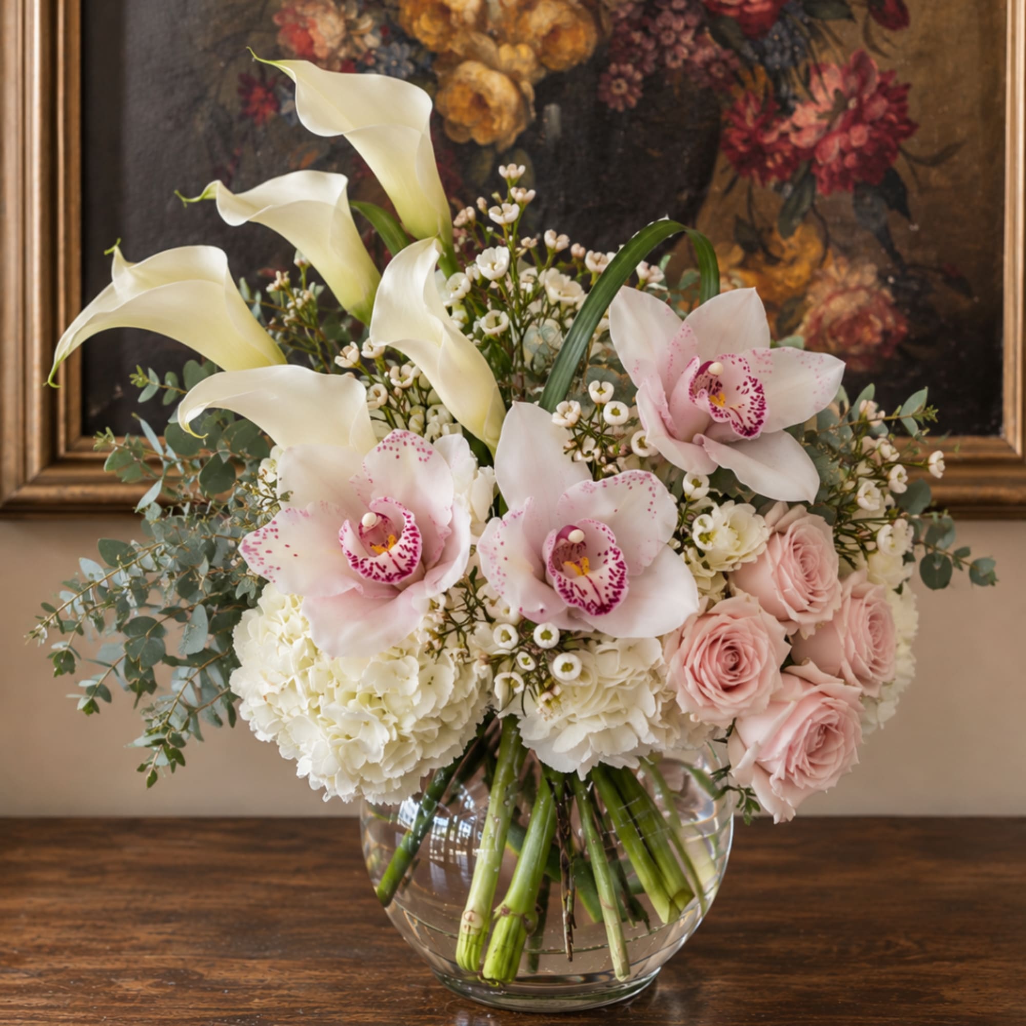 Bouquet of white calla lilies, pink orchids, and pale roses in a glass vase