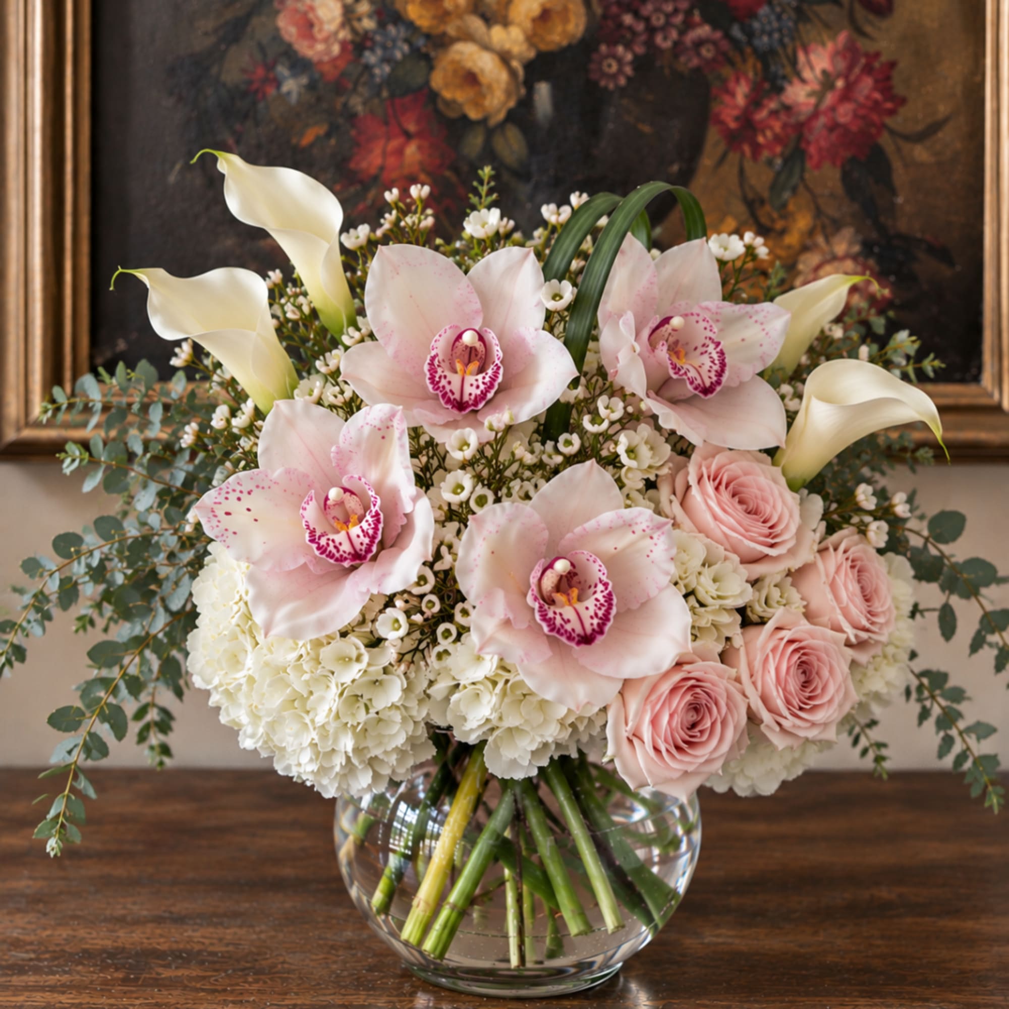 Pink orchids, roses, and white calla lilies in a glass vase