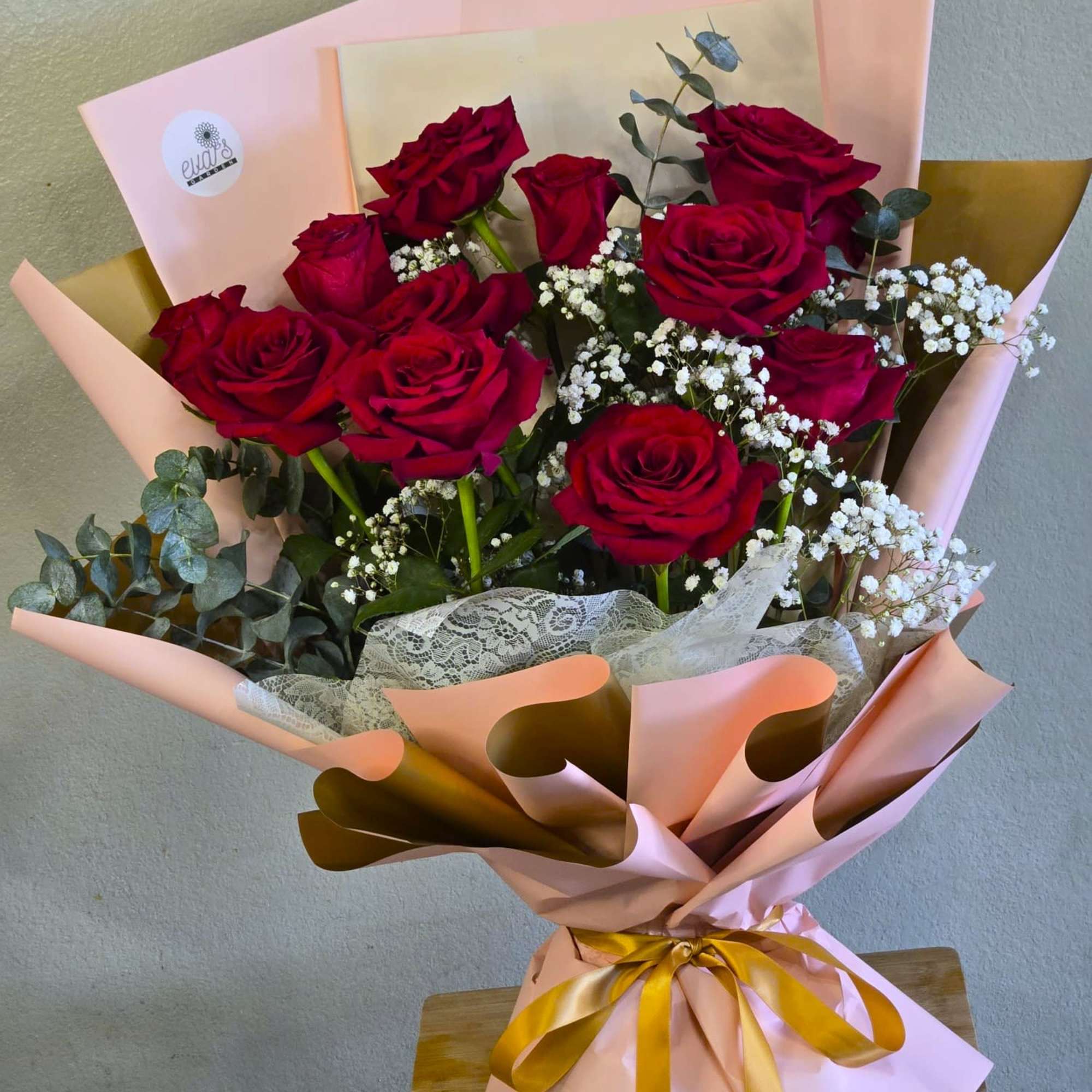Bouquet of red roses with baby's breath in pink and gold wrapping