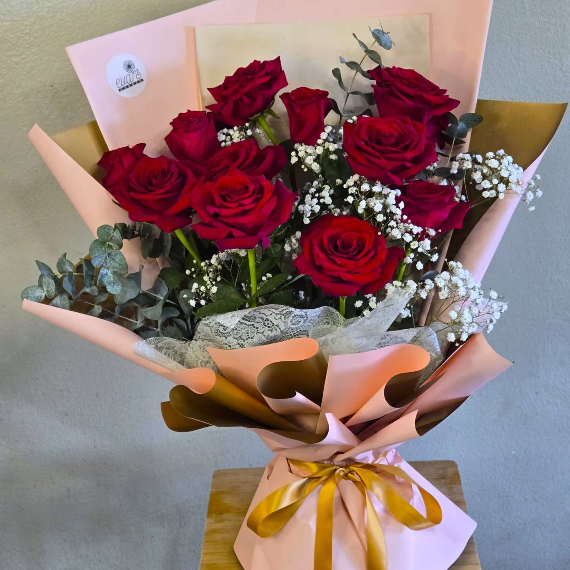 Bouquet of red roses with white baby's breath in pink and gold wrapping
