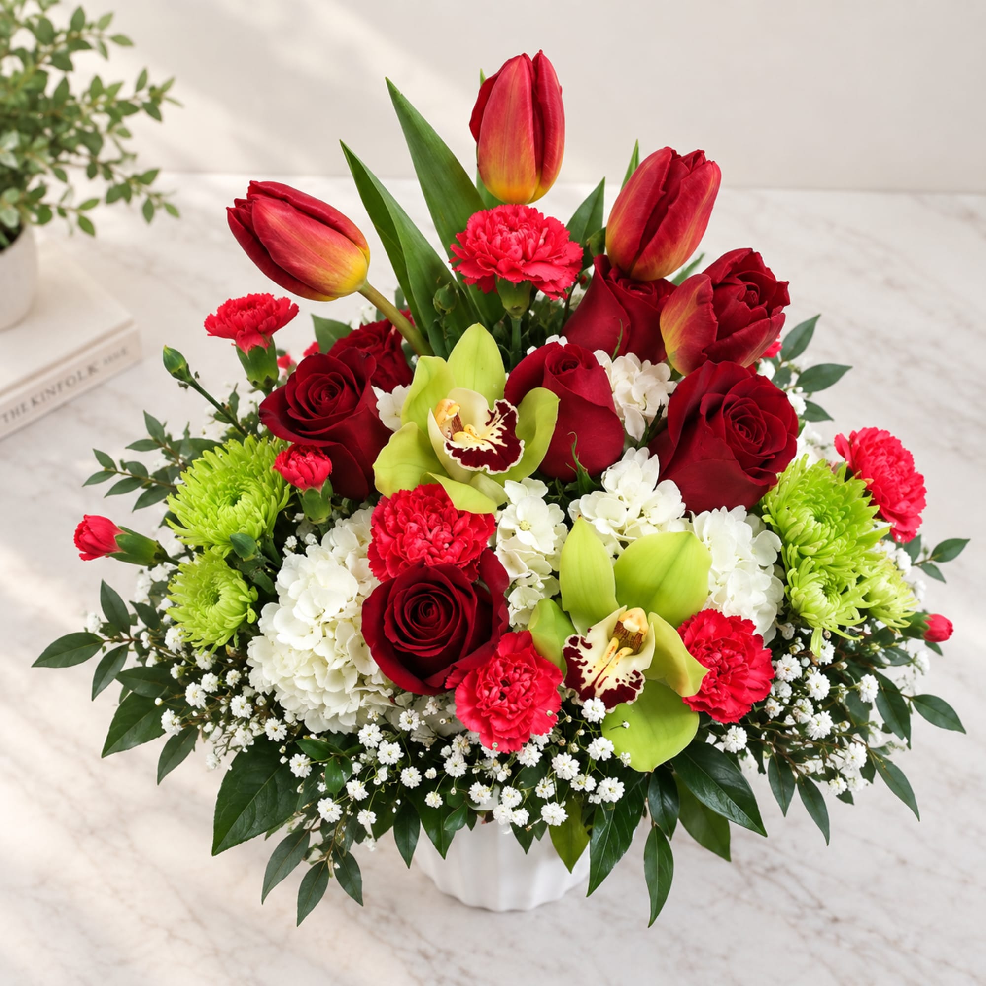 Red roses, tulips, carnations, and orchids in a white vase