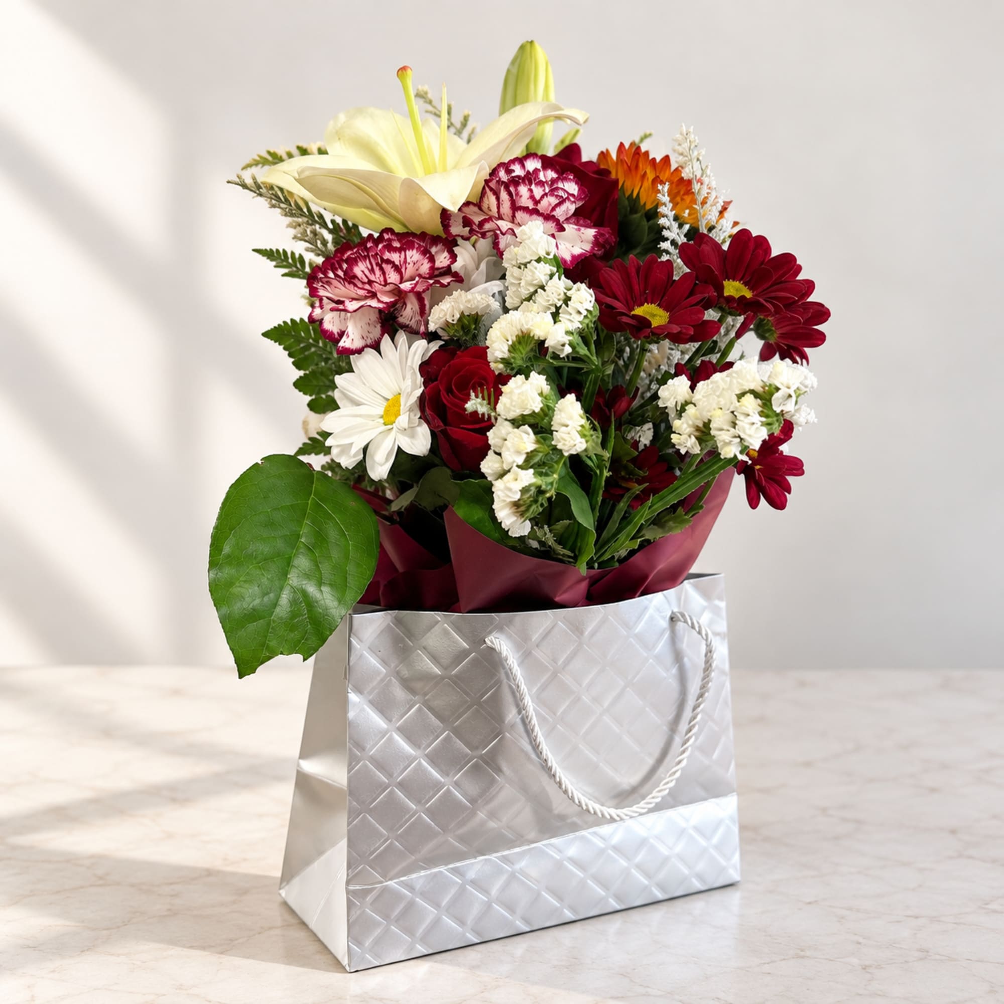 Mixed bouquet of lilies, carnations, daisies, and roses in a gift bag