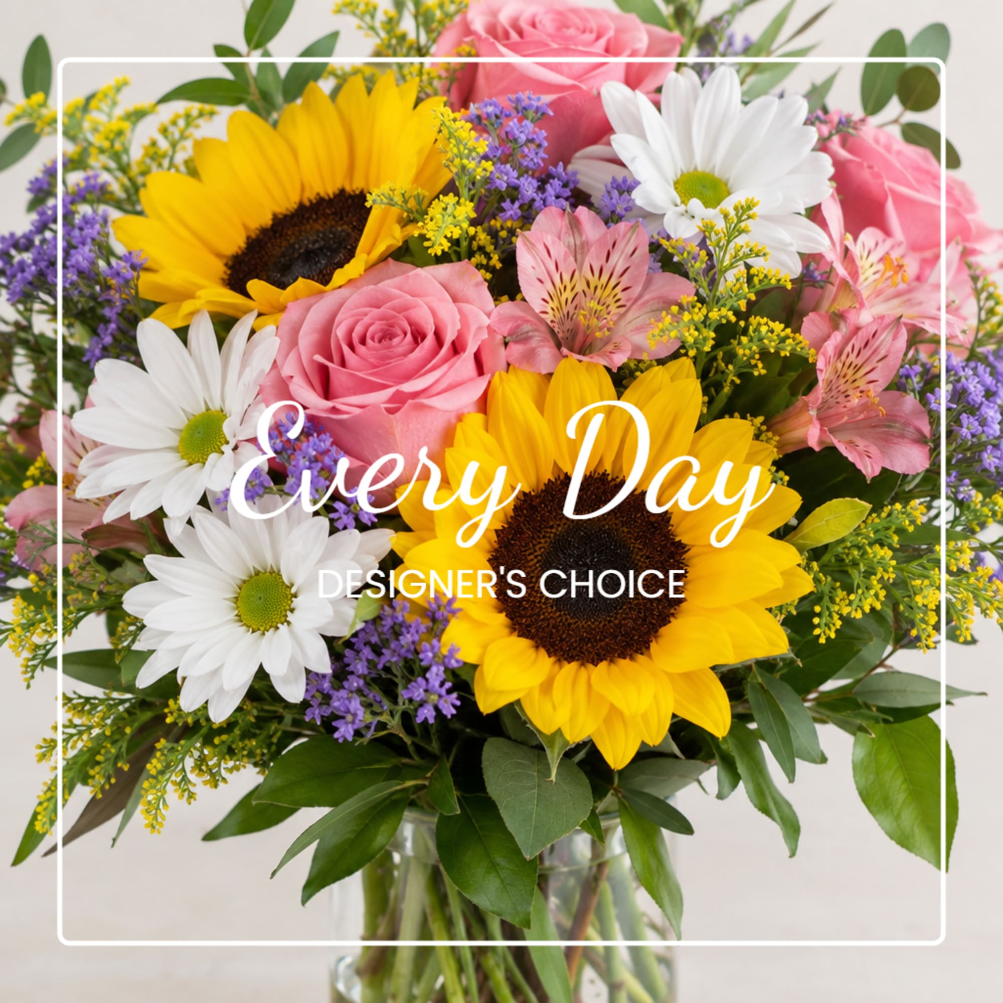 Mixed bouquet with sunflowers, pink roses, white daisies, and purple filler in a glass vase