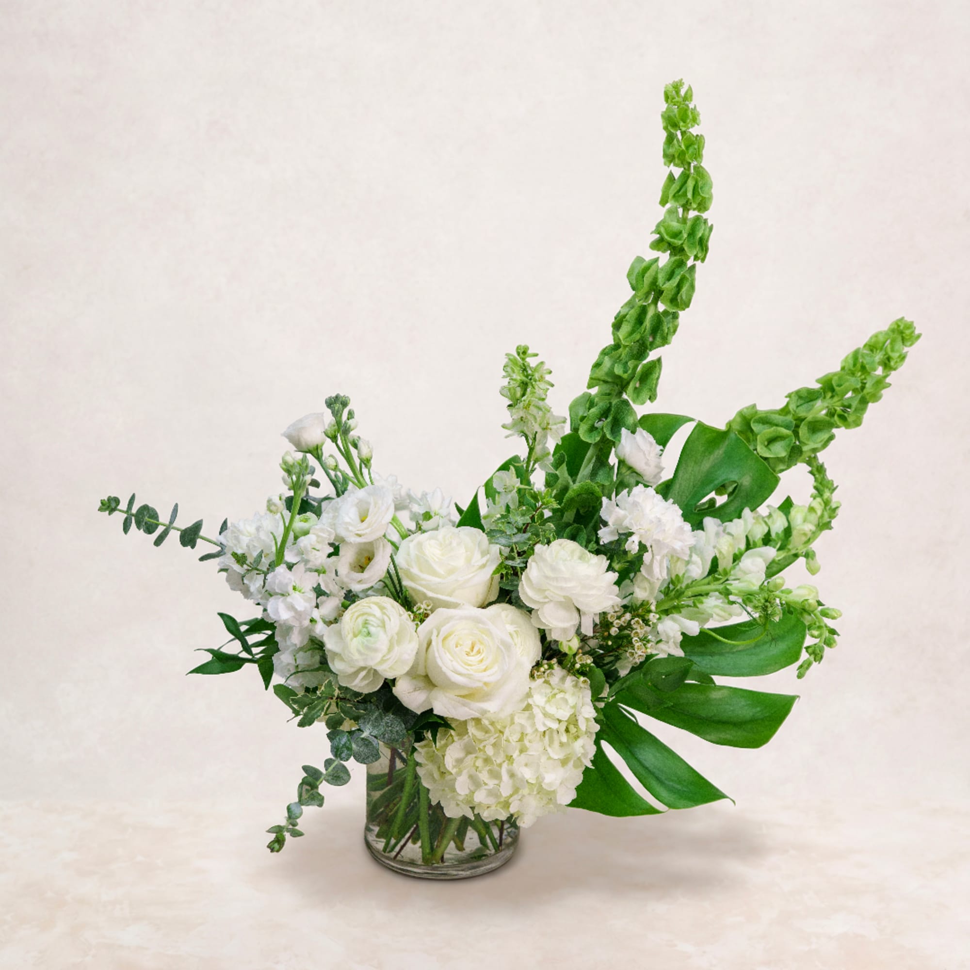 White floral arrangement in a clear glass vase with tall green spikes, photo 4 of 4