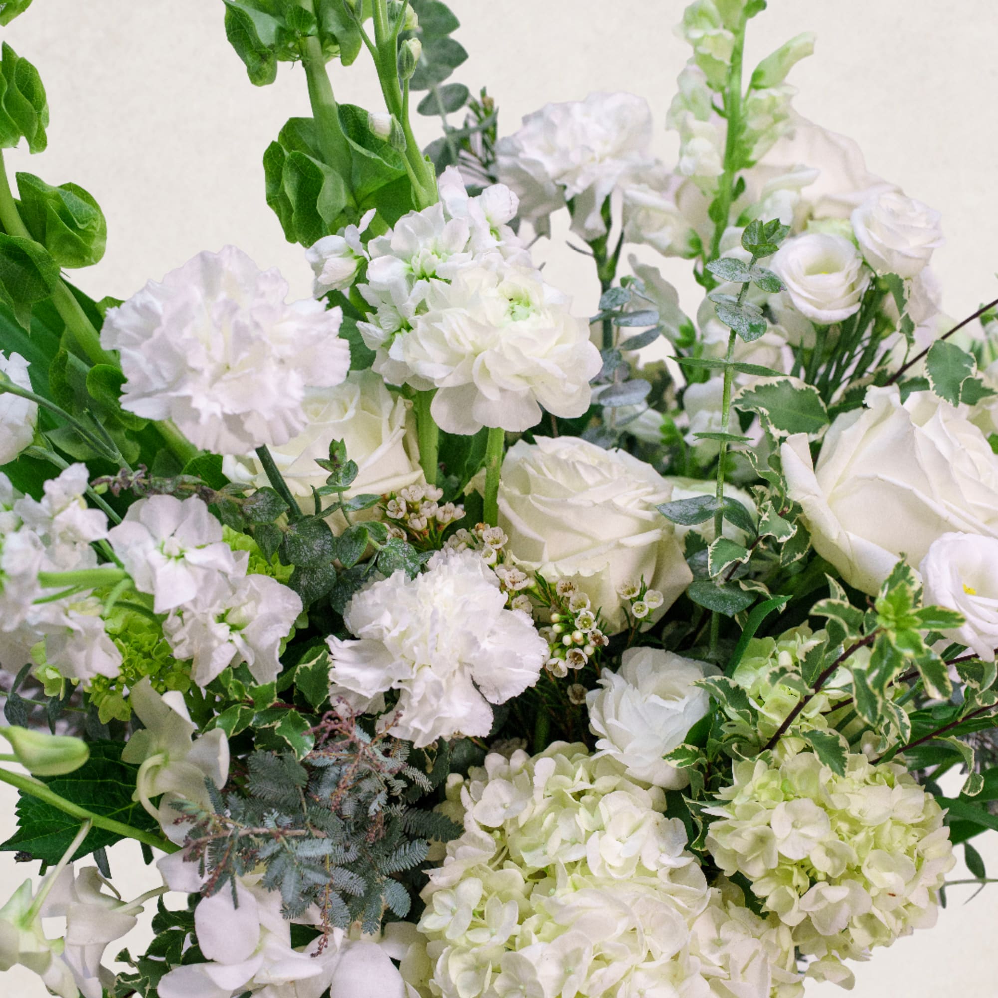 White roses and carnations with green foliage in a bouquet