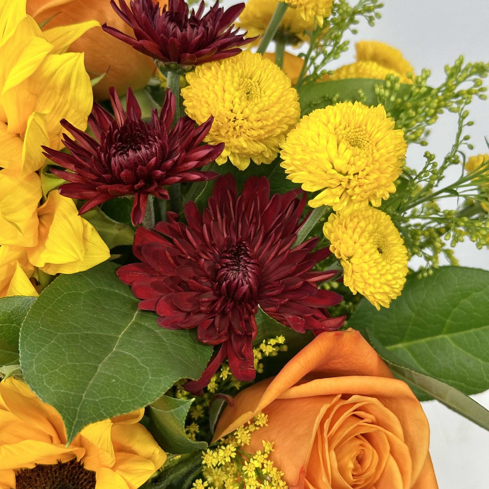 Bouquet with orange roses, yellow sunflowers, and burgundy chrysanthemums