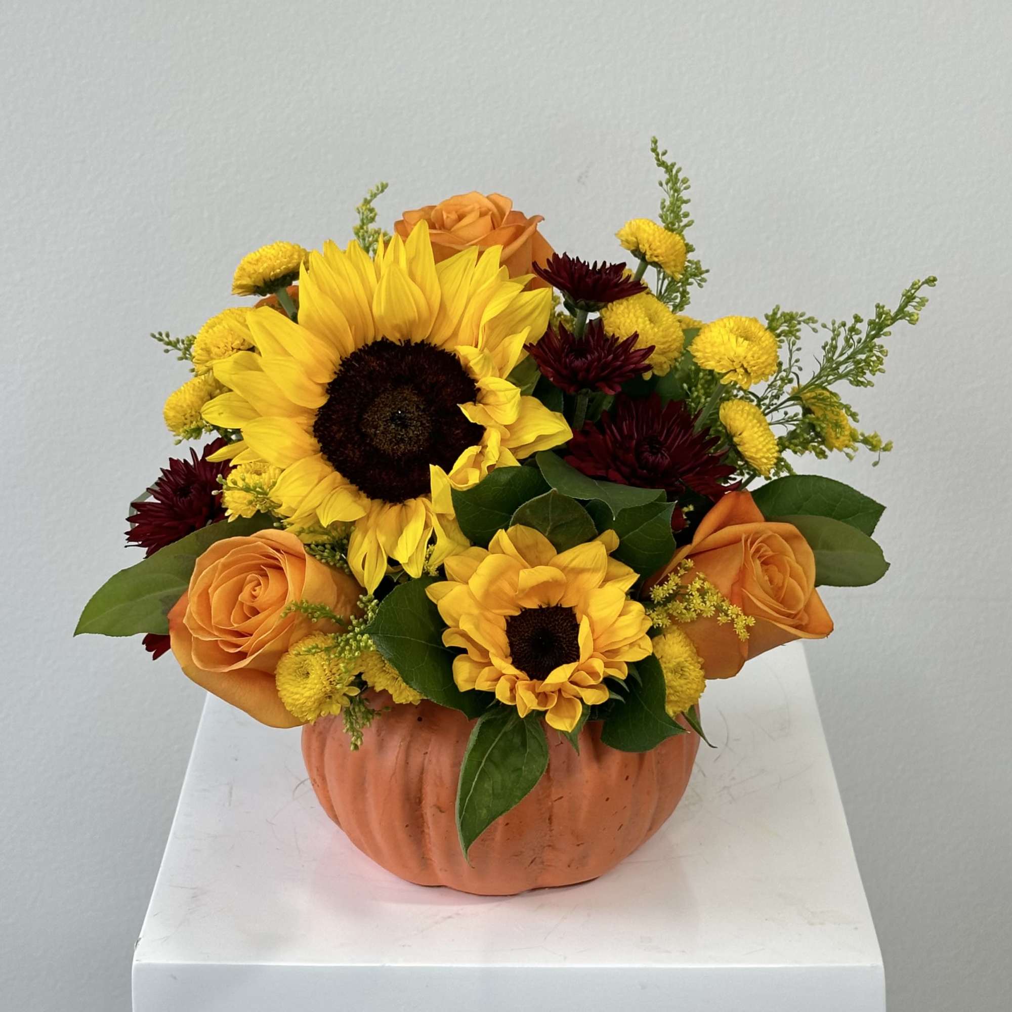 Sunflowers and orange roses in a pumpkin-shaped container