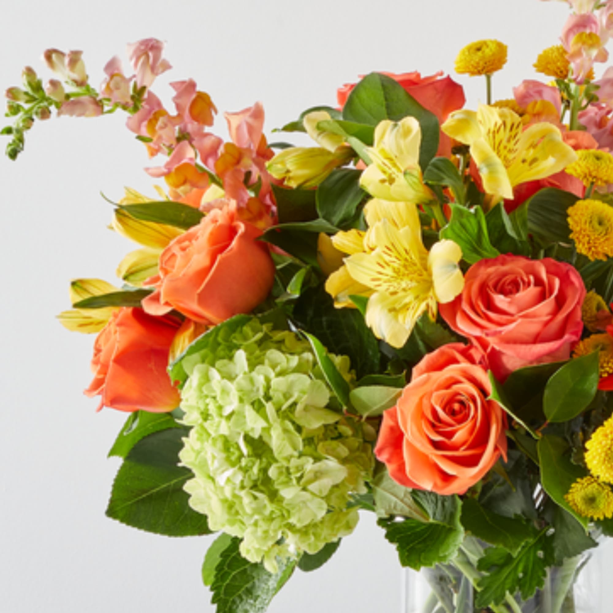Colorful bouquet of roses, lilies, and hydrangea in a glass vase