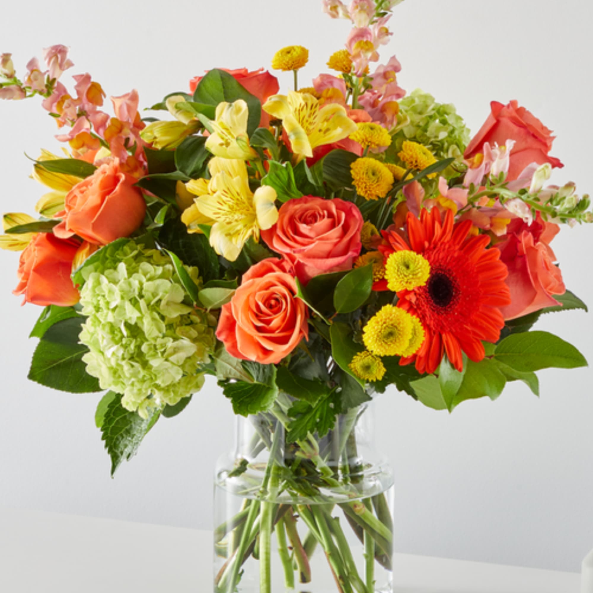 Mixed bouquet of orange and yellow flowers in a clear glass vase