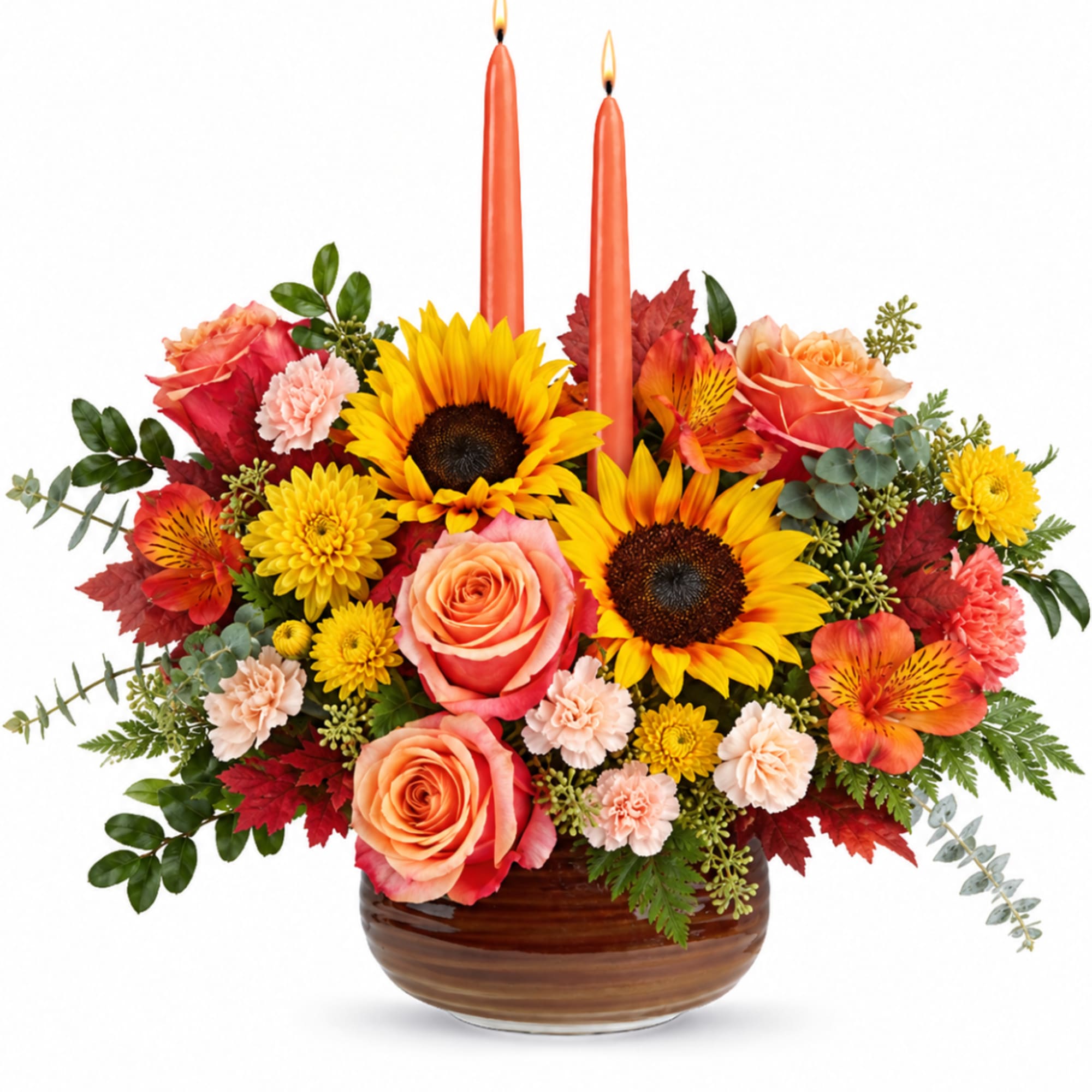 Orange floral arrangement with sunflowers, roses, and candles in a brown vase