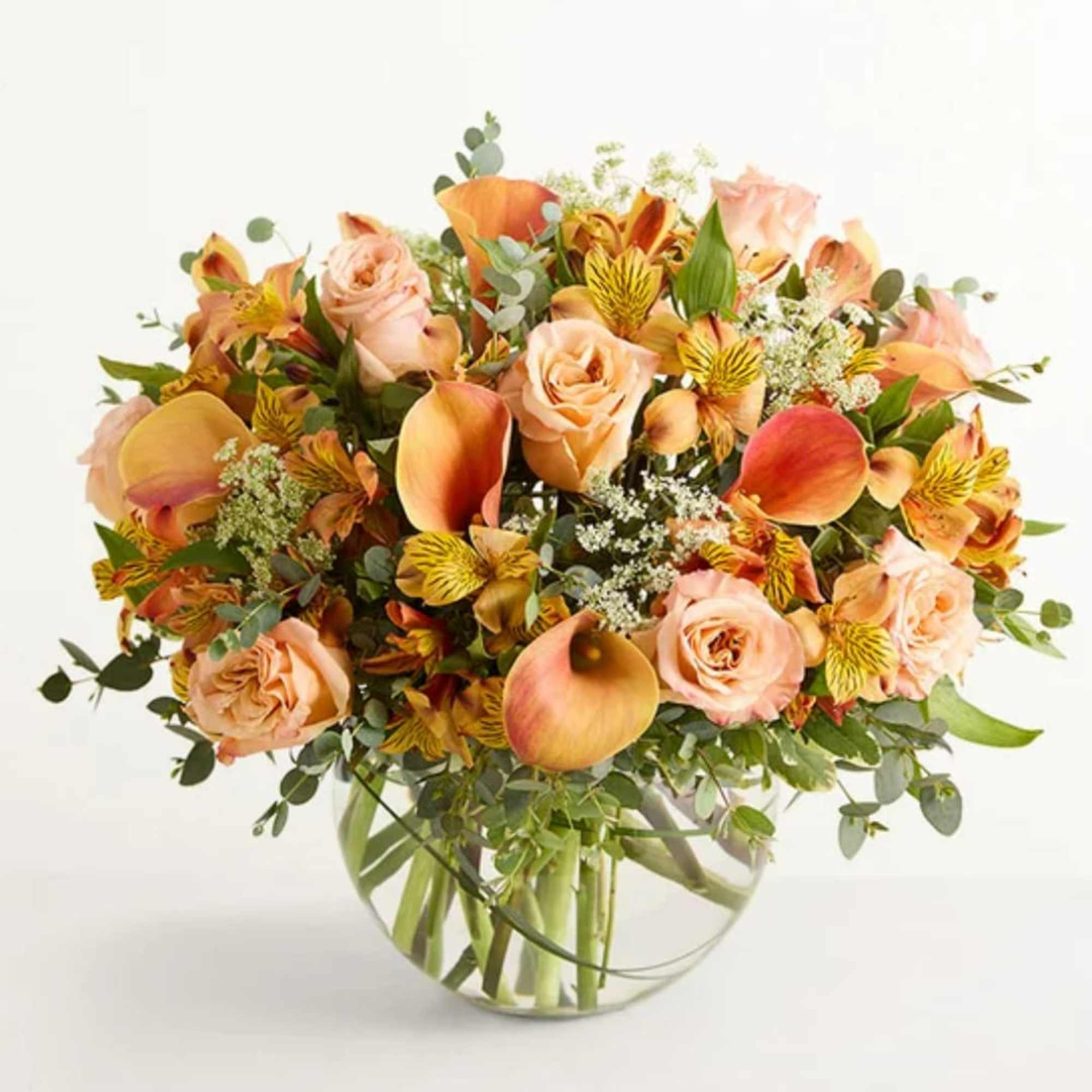 Soft peach roses and vibrant orange calla lilies mingle with sunny yellow-striped