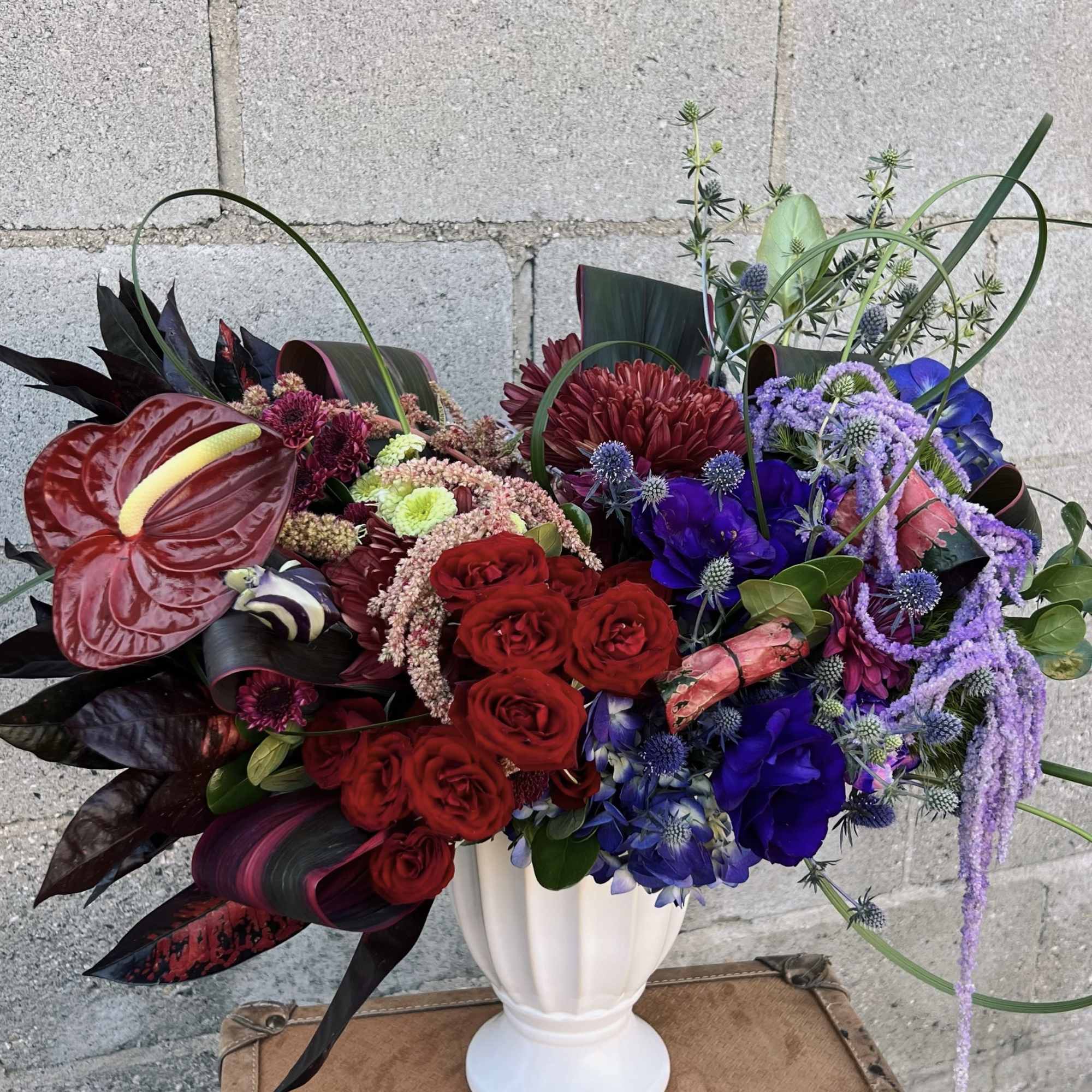 Bold mixed bouquet in a white vase with red, purple, and blue flowers