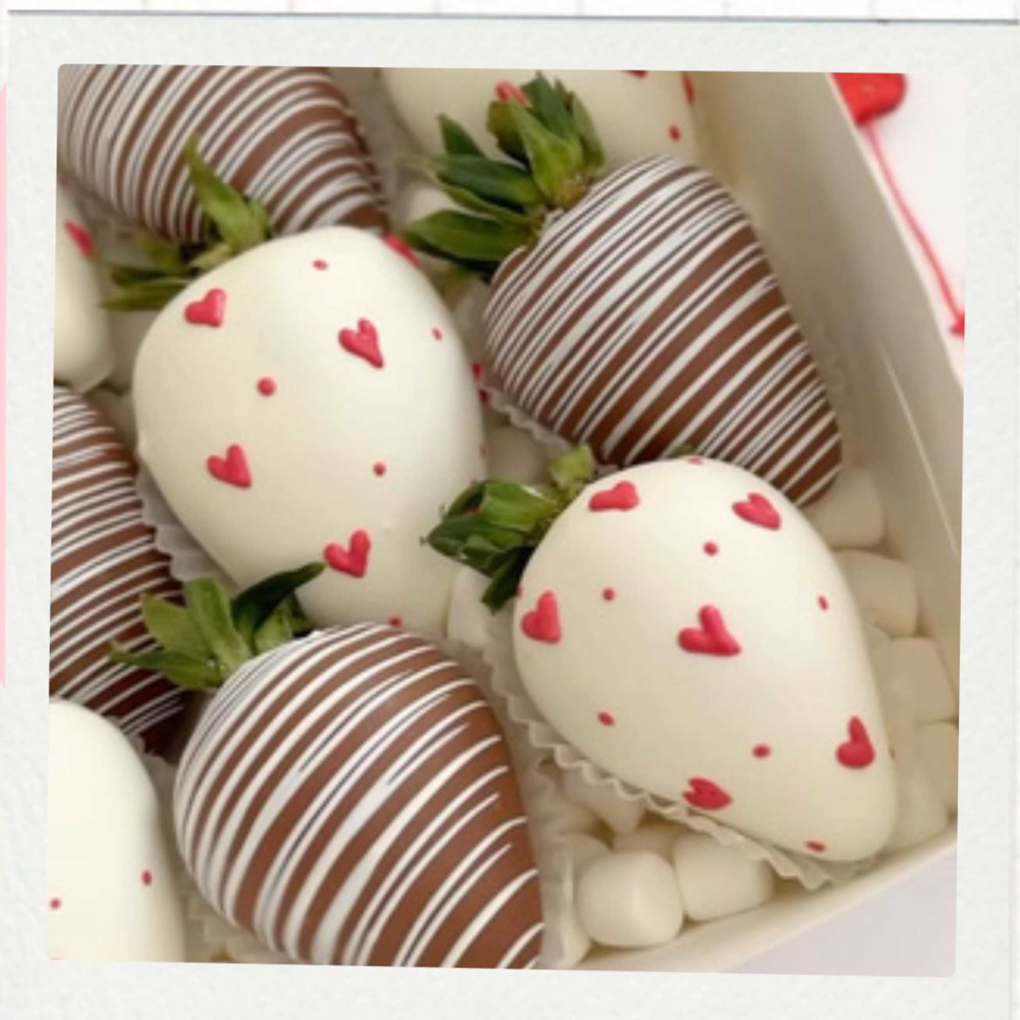 Box of chocolate-covered strawberries with heart decorations