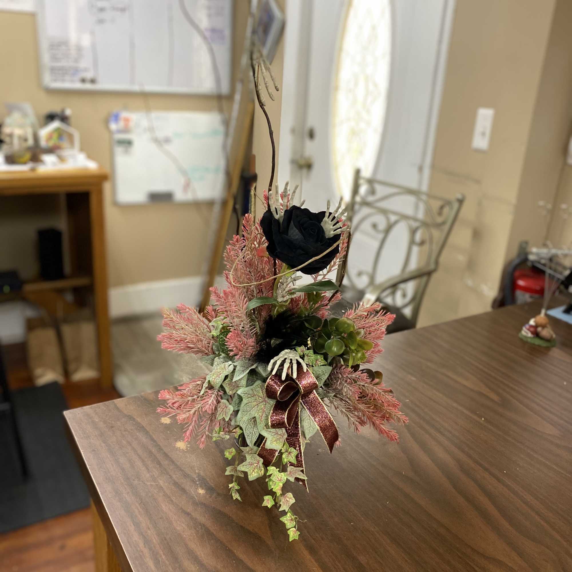 A bud vase filled with a silk black rose and filled with