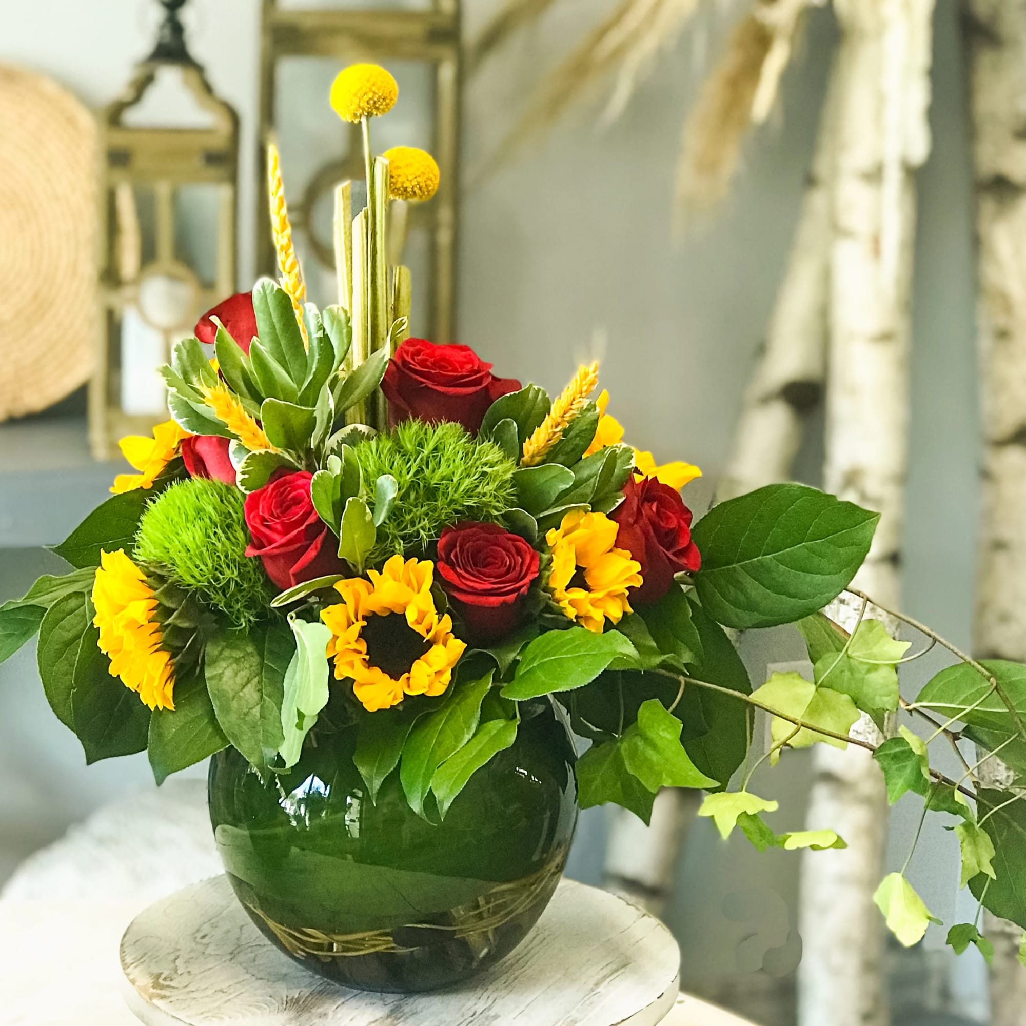 Red roses and yellow flowers arranged in a dark glass vase