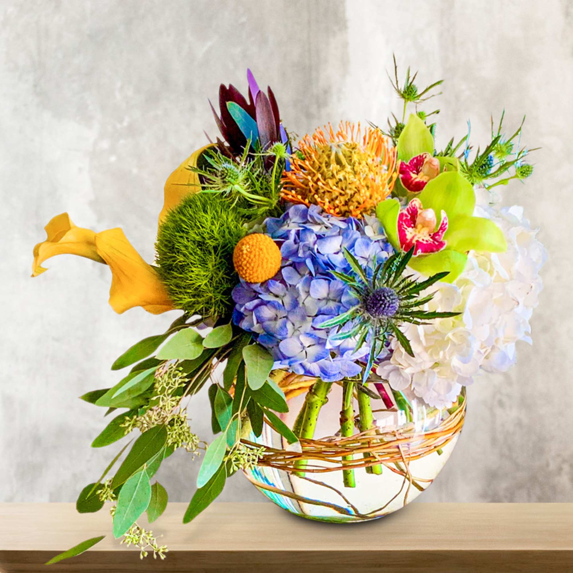 Colorful mixed bouquet in a round glass vase with a wicker wrap