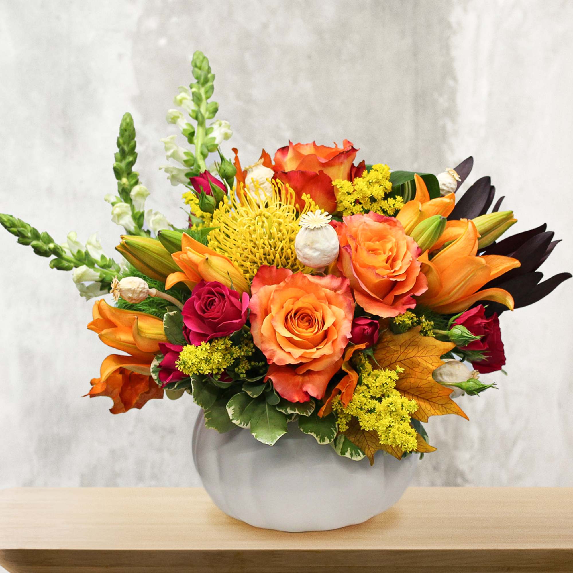 Orange and red roses with lilies in a white vase