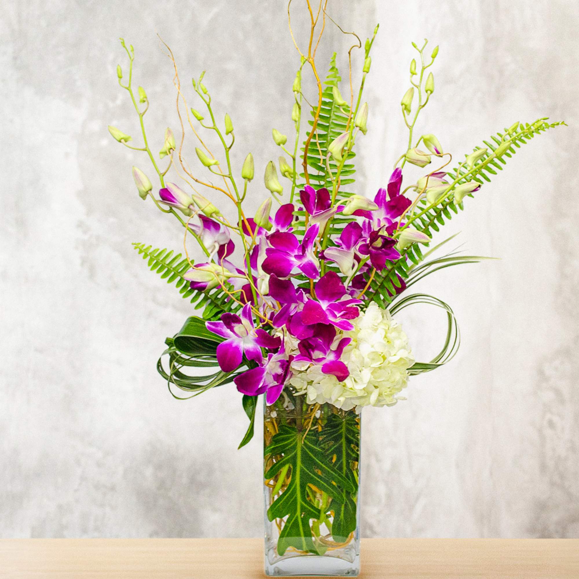 Purple orchids and white hydrangea in a tall glass vase