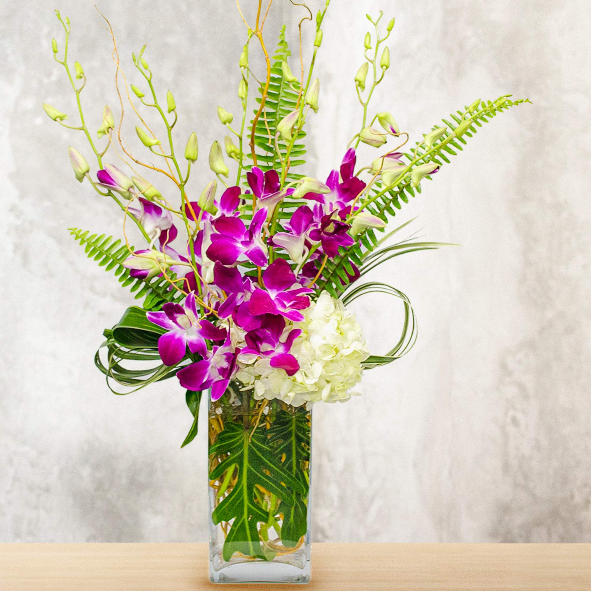 Purple orchids and white hydrangea in a clear rectangular vase