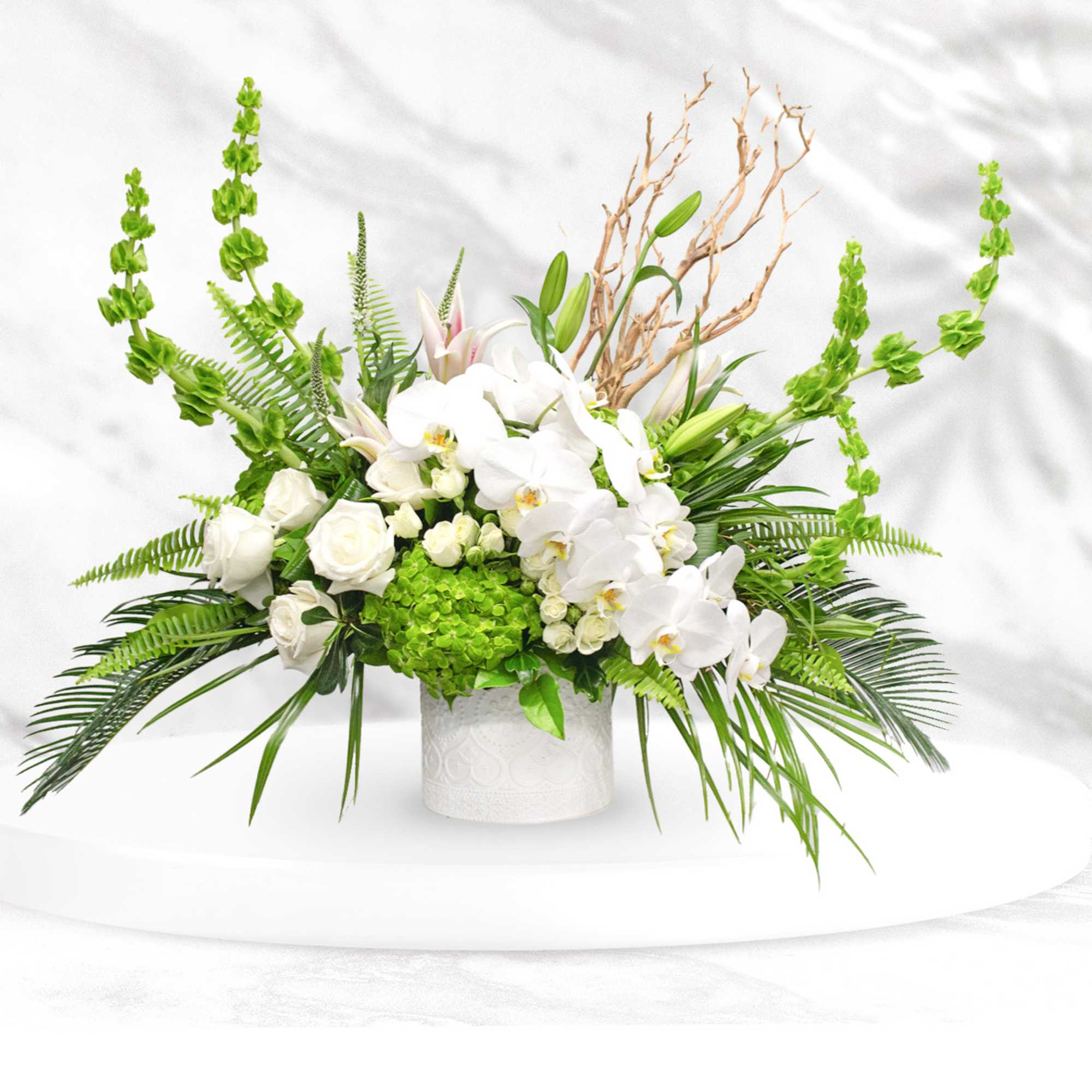 White orchids and roses in a white vase with bright green accents