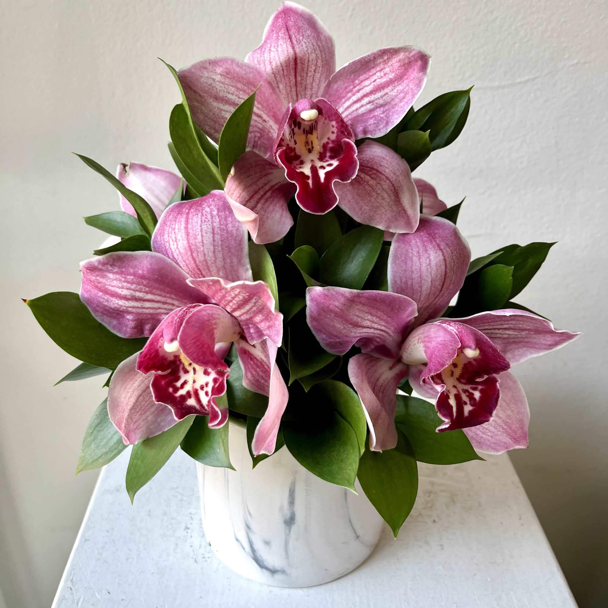 Pink orchids arranged in a white ceramic pot
