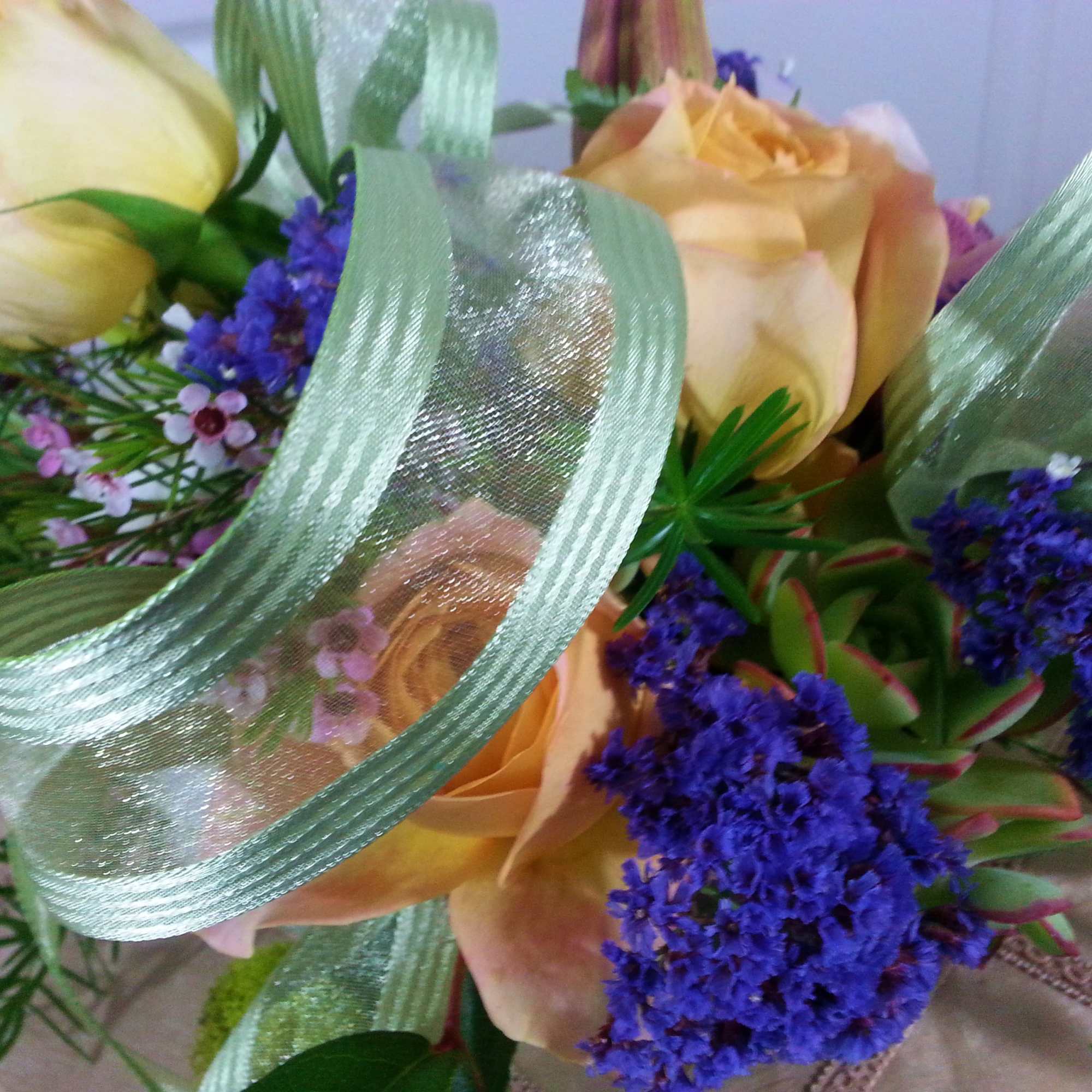 Bouquet of peach roses with purple filler flowers and green ribbon