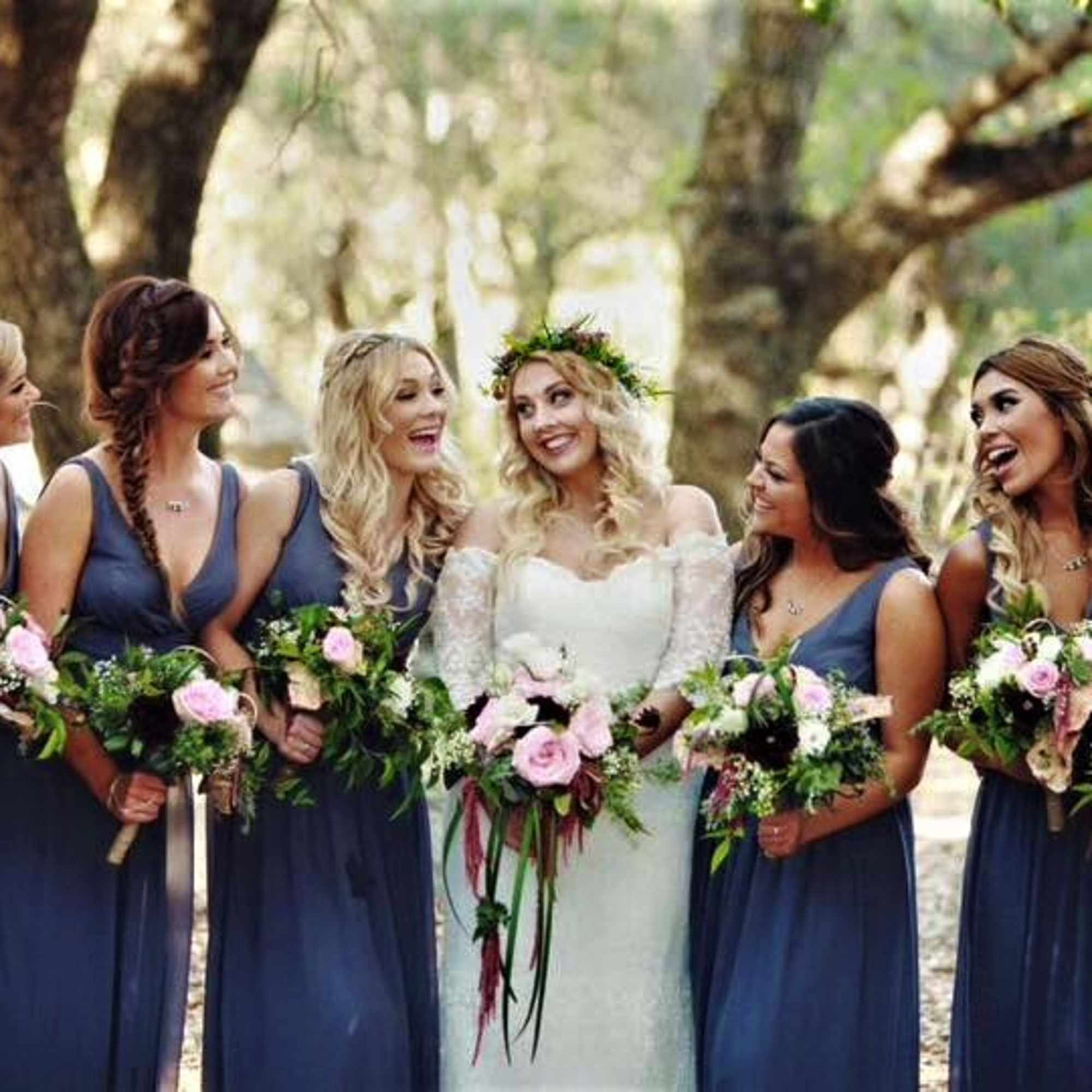 Bride with bridesmaids holding pink and white bouquets outdoors