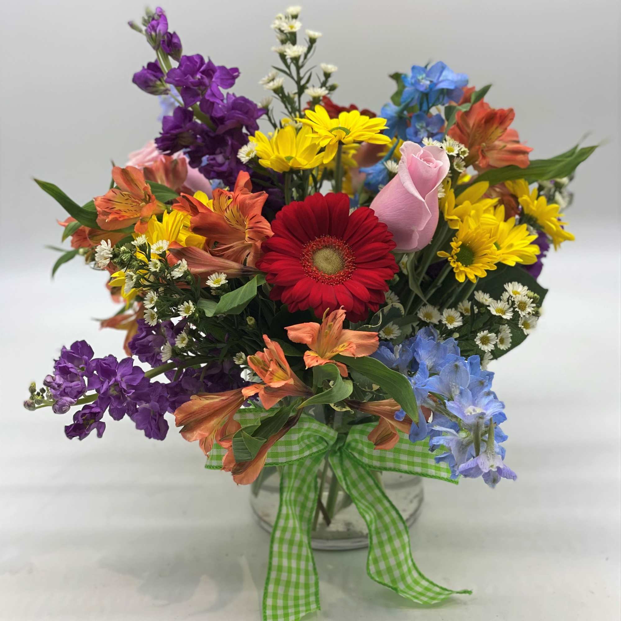 Colorful mixed bouquet in a clear glass vase with a green gingham ribbon