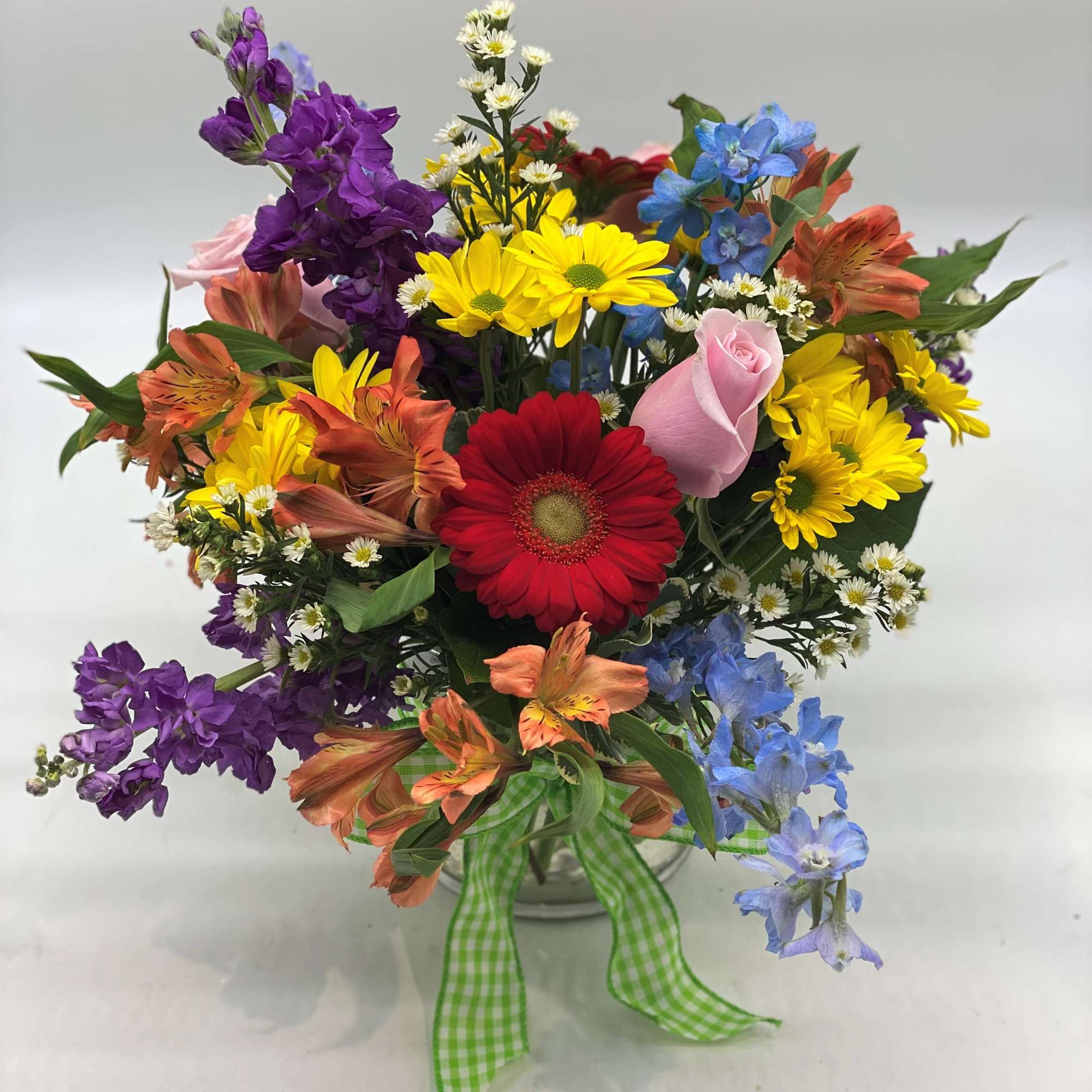 Mixed bouquet with gerbera daisies, roses, and alstroemeria in a glass vase