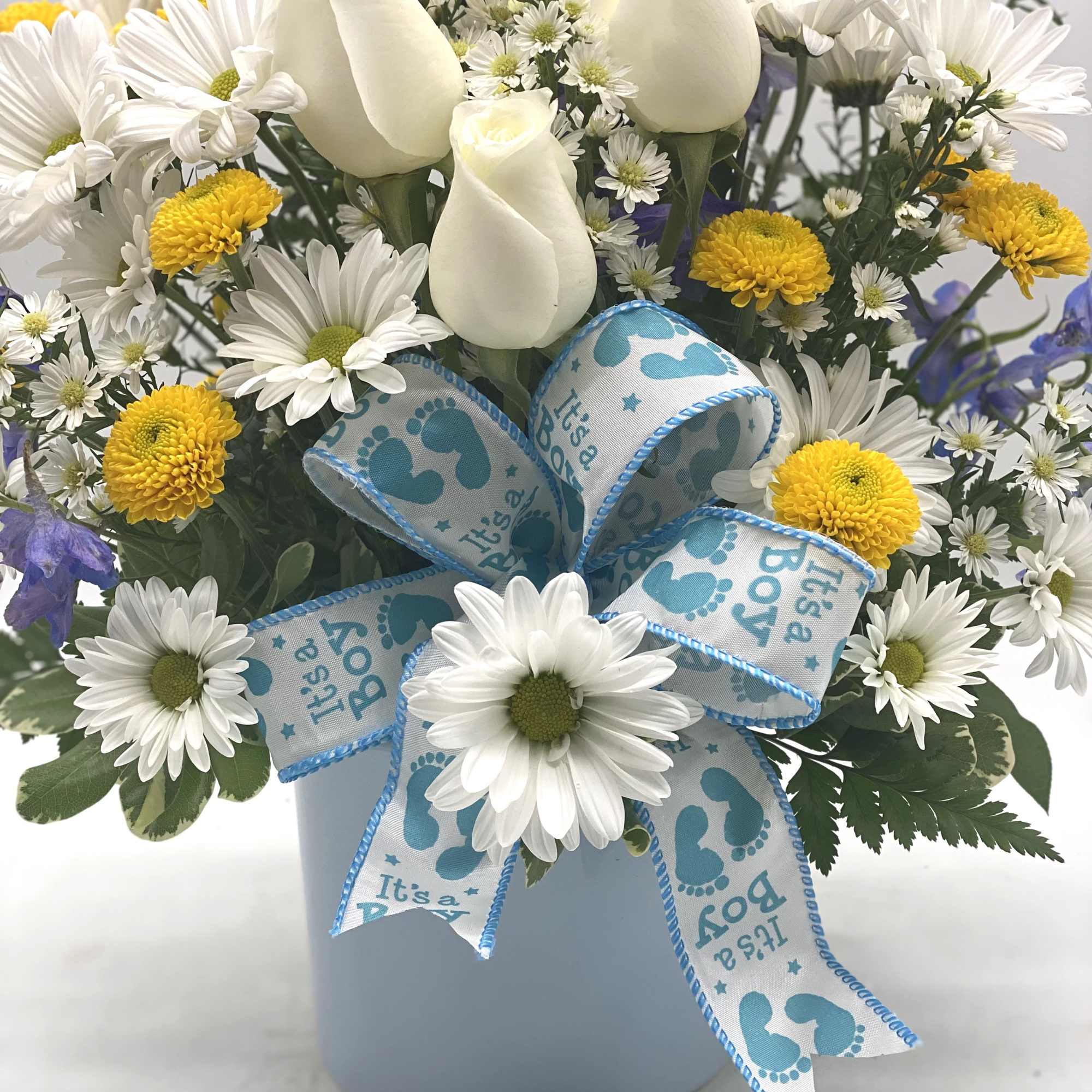 White roses and daisies in a blue vase with a baby boy ribbon