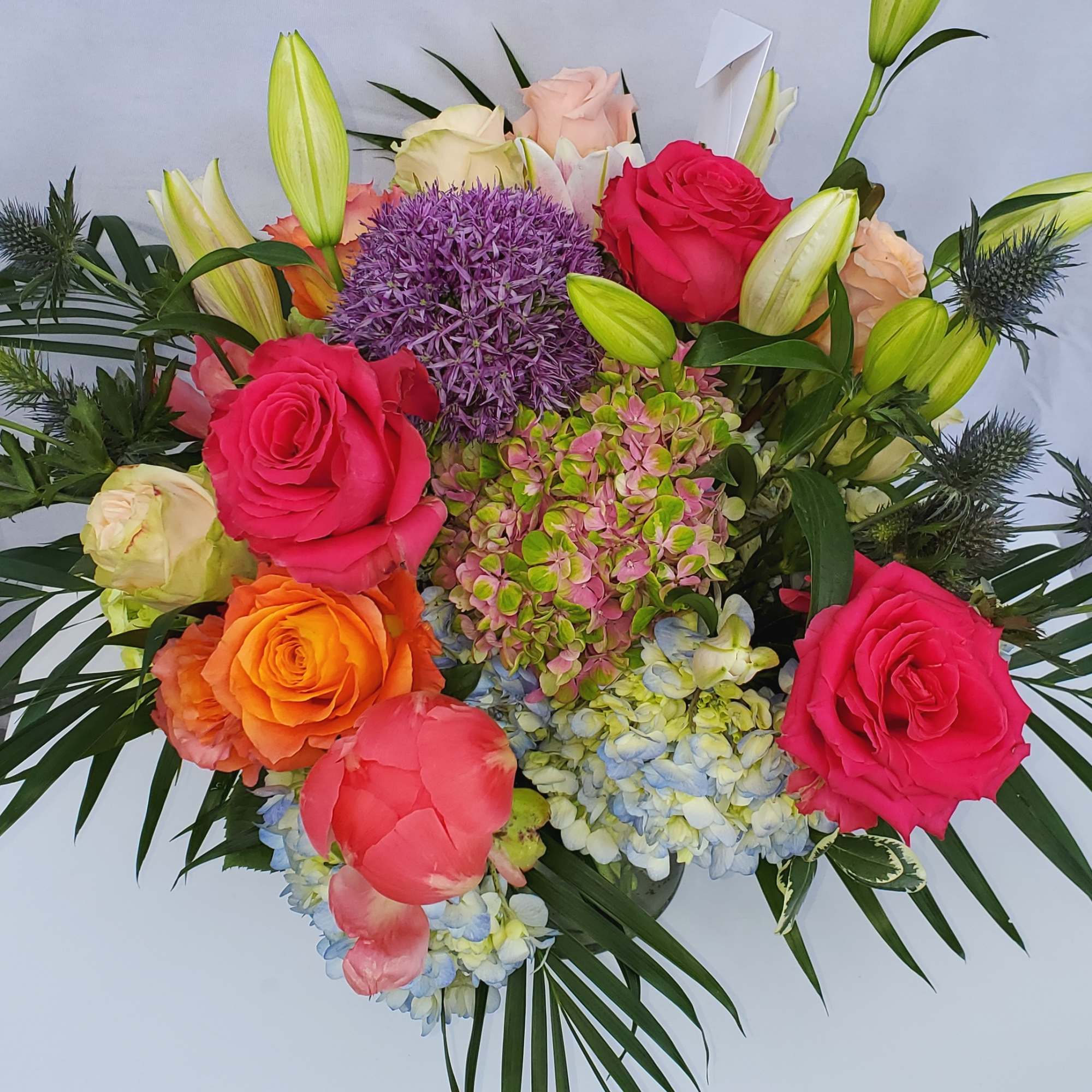 Colorful arrangement of roses, lilies, hydrangeas, and peonies in a bright mixed palette