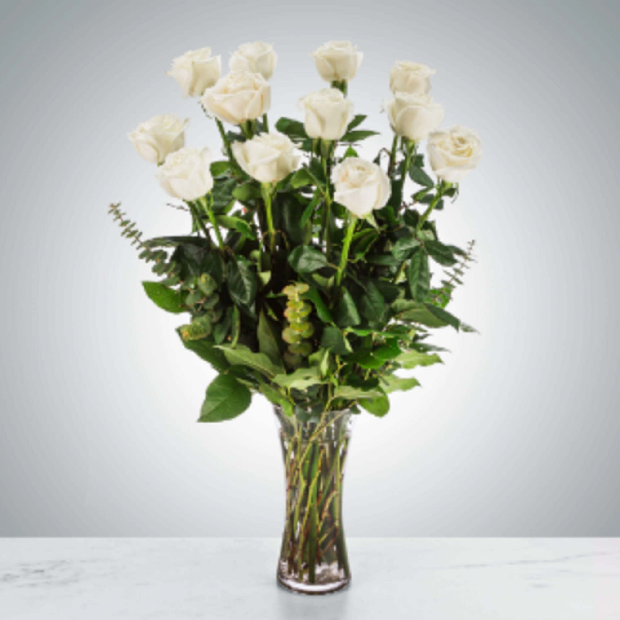 Tall arrangement of white roses in a clear glass vase
