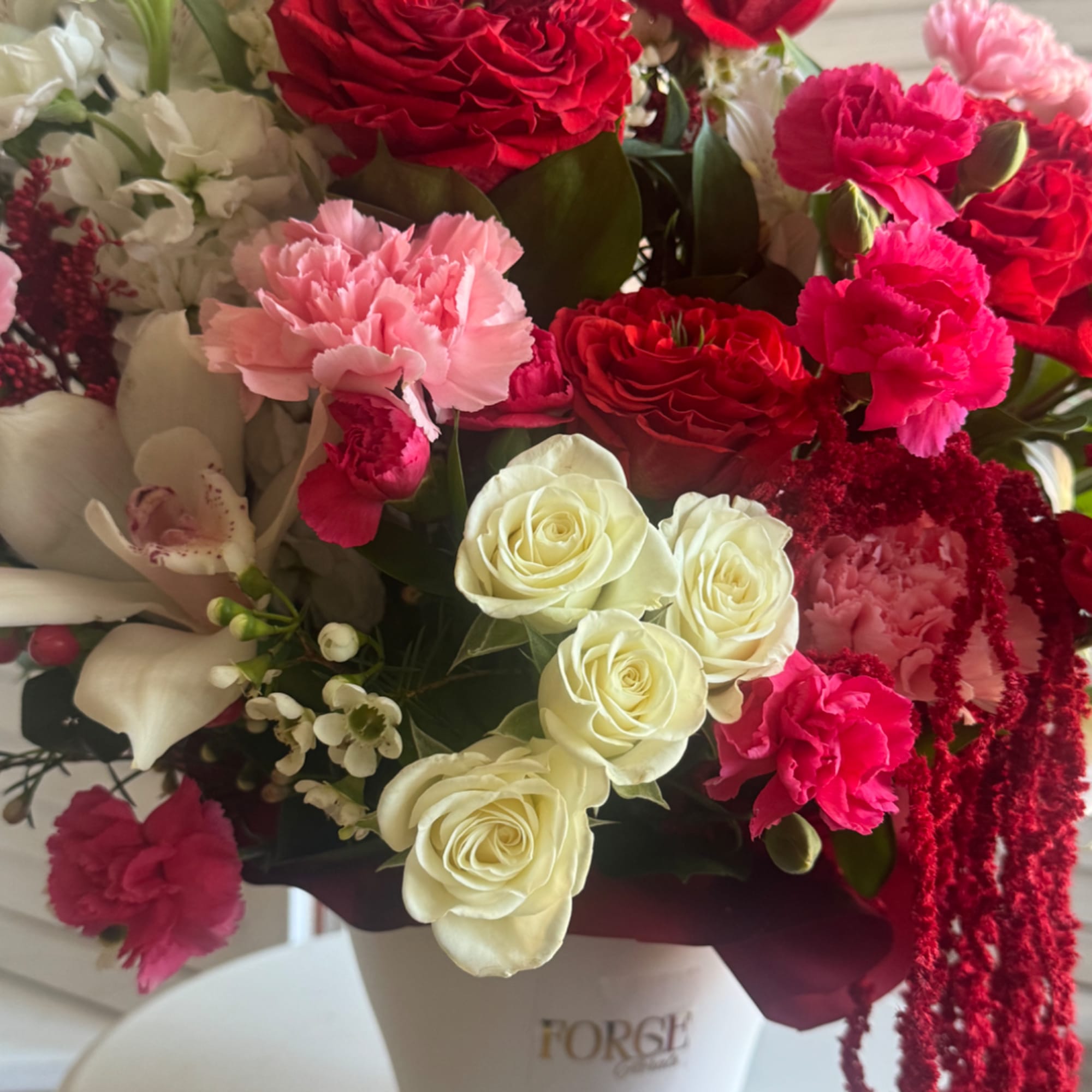 Mixed bouquet of red, pink, and white flowers in a white vase