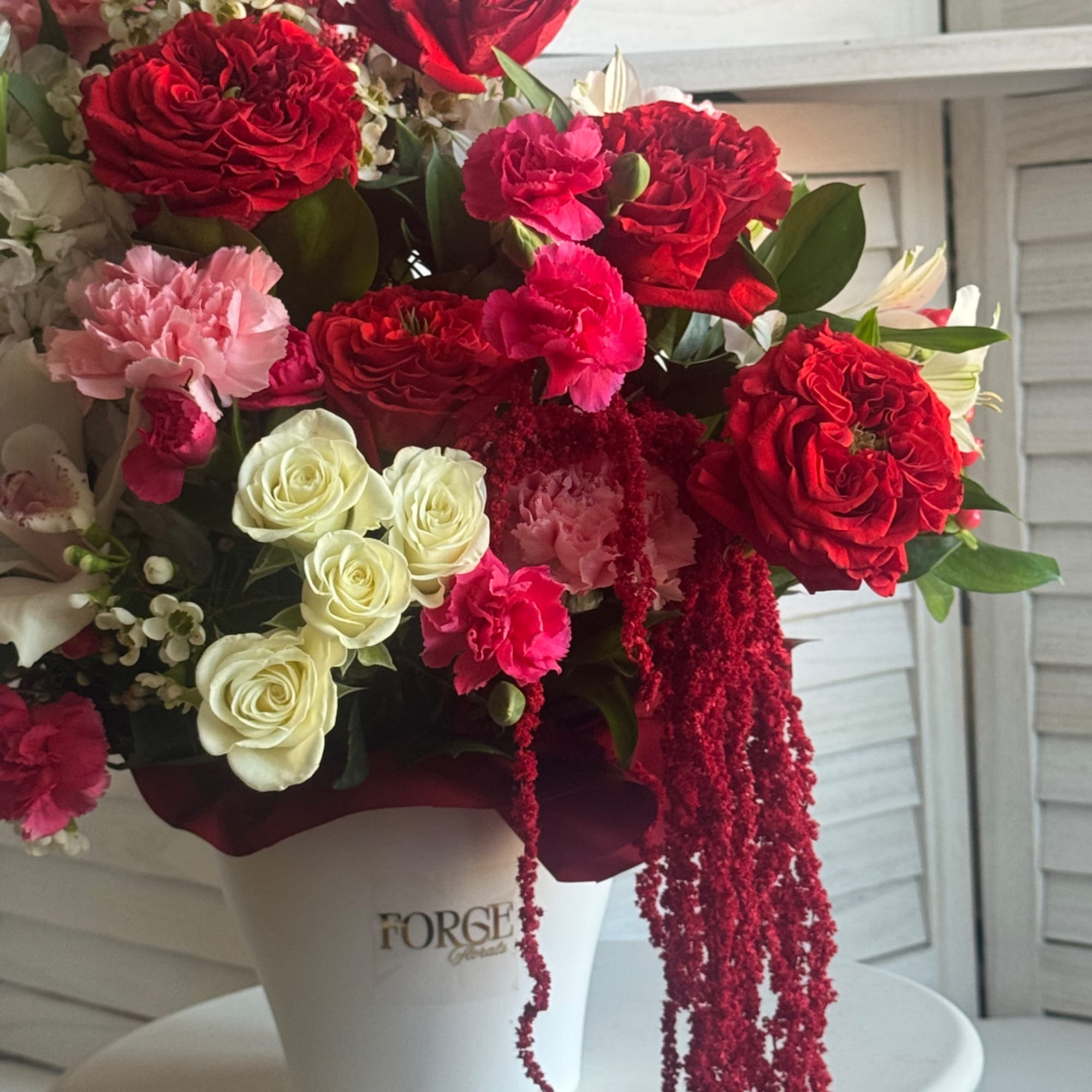 Bouquet of red and pink roses with white blooms in a white vase