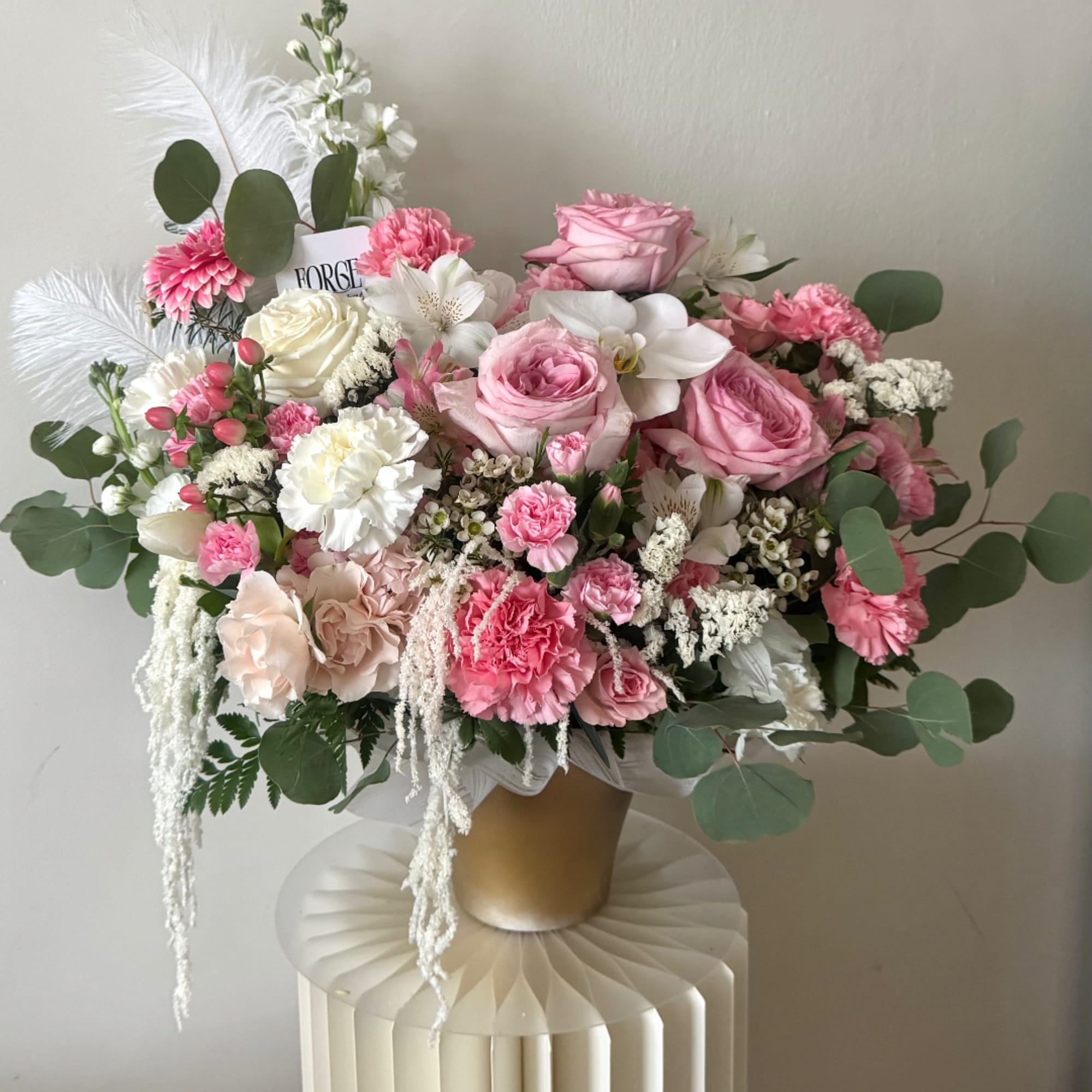 Pink and white floral arrangement in a gold vase with eucalyptus