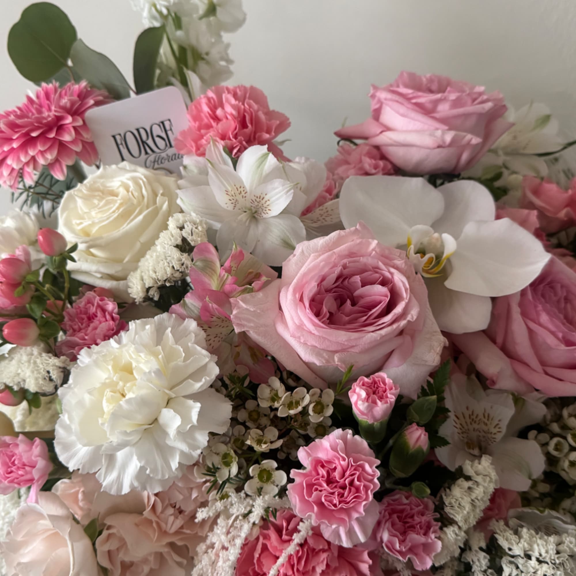 Pink and white bouquet with roses, carnations, and orchids
